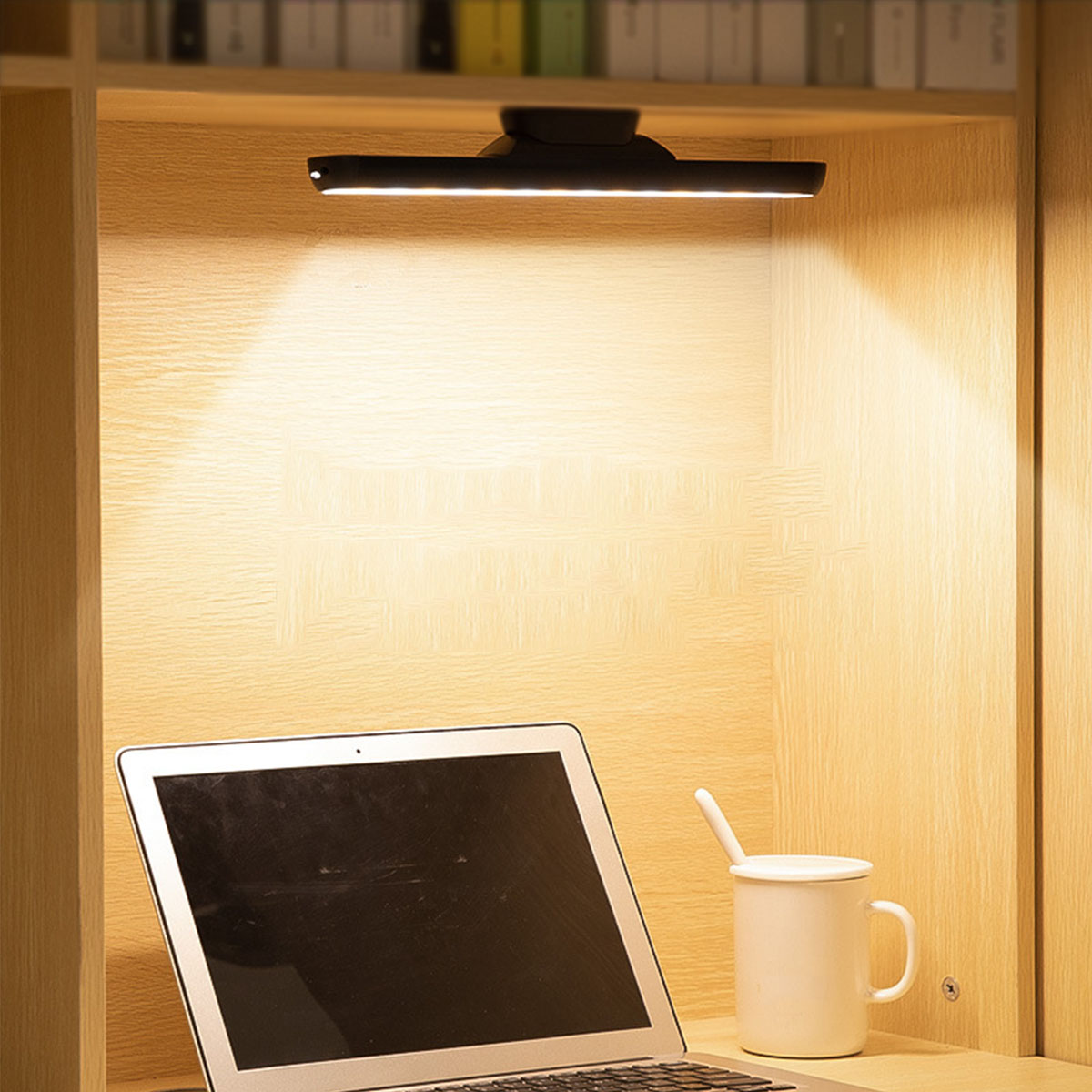 Eine schwarze Schreibtischlampe, die ein Holzregal mit einem Laptop und einem Becher beleuchtet.