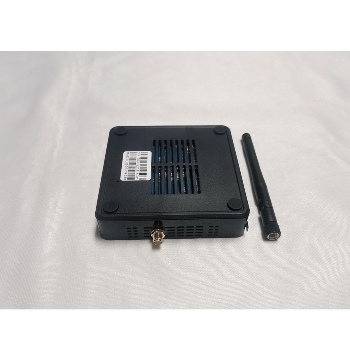 Ein schwarzes Gerät mit Antenne und Anschlüssen auf weißer Oberfläche. Das Gerät ist rechteckig.