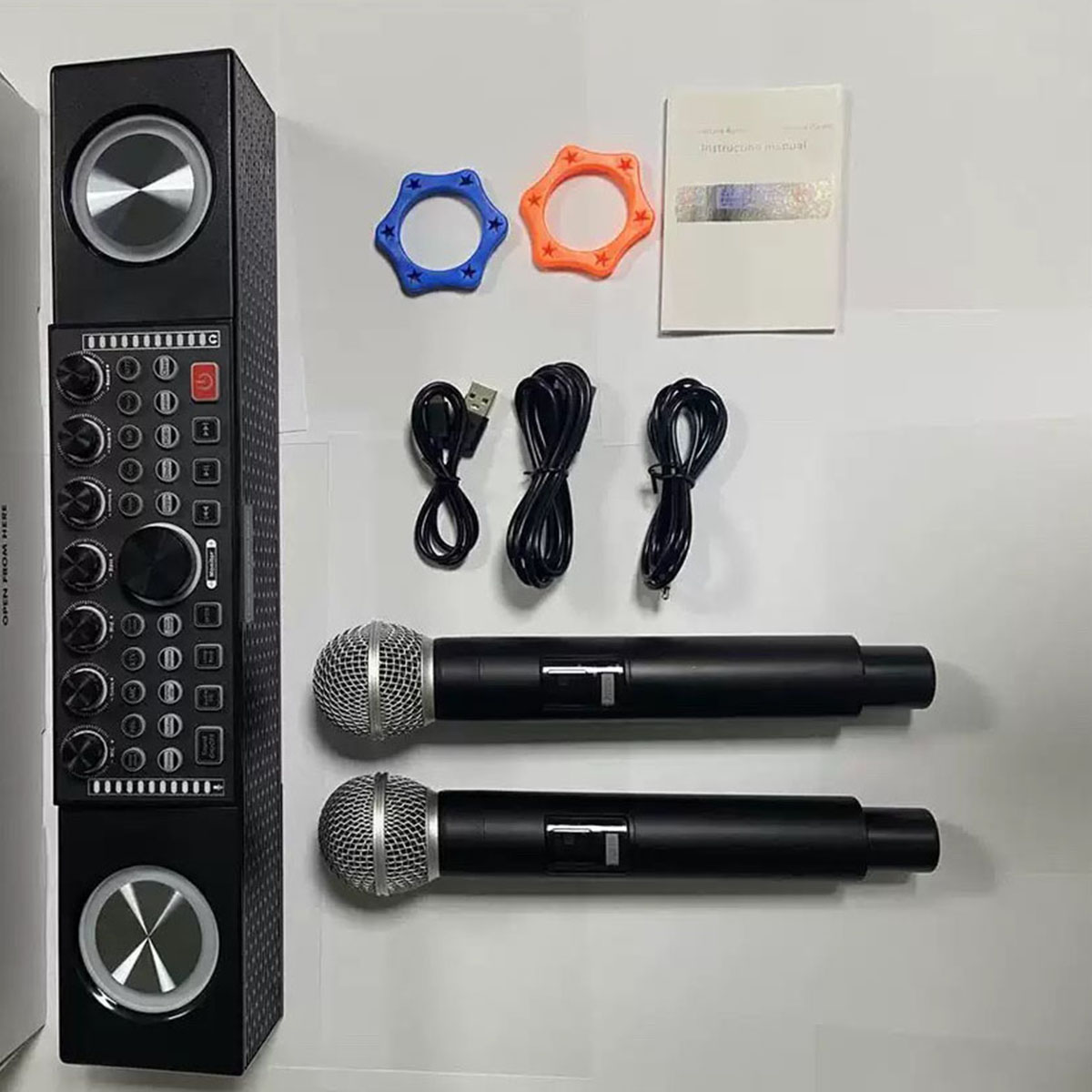 Eine Karaoke-Maschine mit Mikrofonen, Kabeln und Zubehör, angeordnet auf einer weißen Oberfläche.