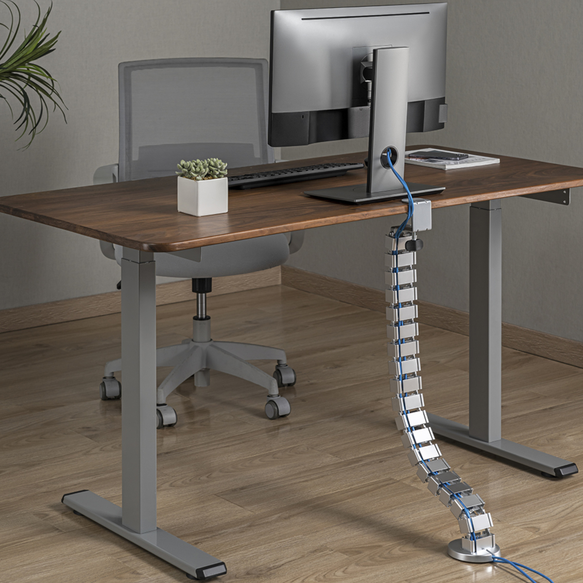Ein Schreibtisch mit Monitor, Tastatur und Kabelmanagement. Der Schreibtisch ist aus Holz.