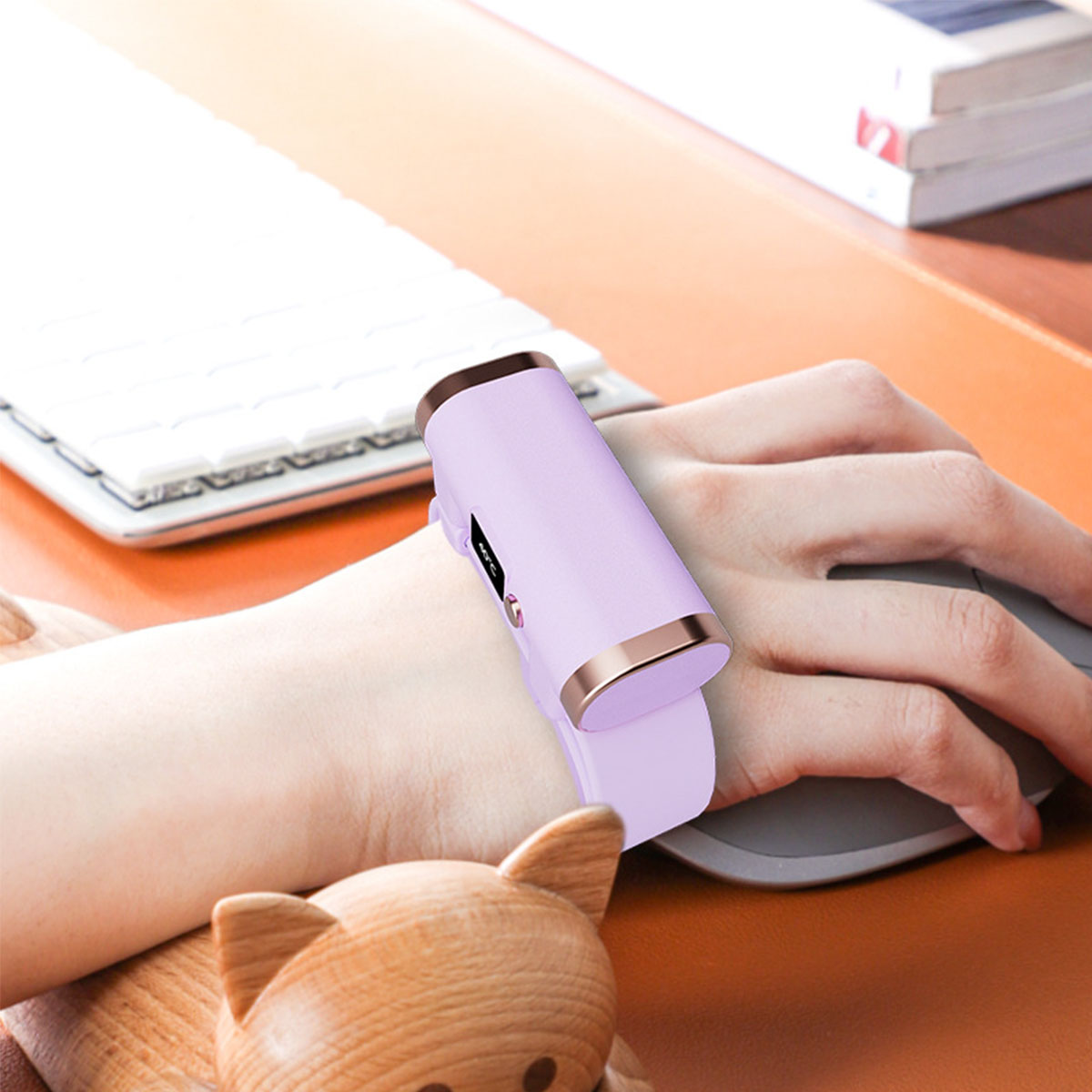 Eine Person, die ein Armbandgerät trägt und eine Maus auf einem Schreibtisch benutzt.