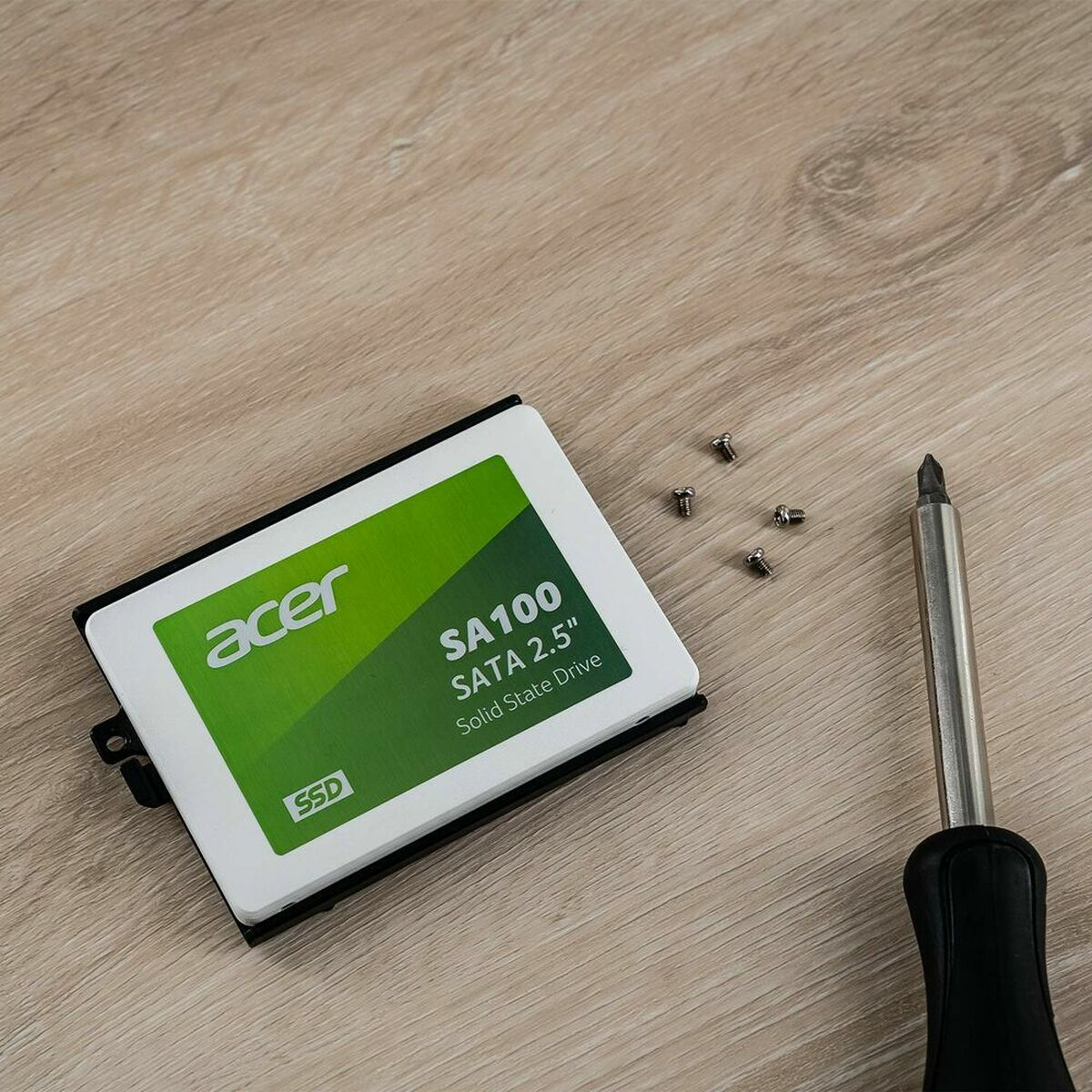 Unità SSD Acer con cacciavite e viti su una superficie di legno.