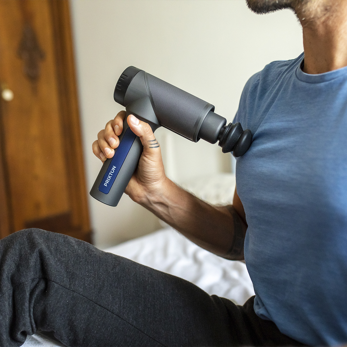 Osoba używająca szarego i czarnego pistoletu do masażu na klatce piersiowej.