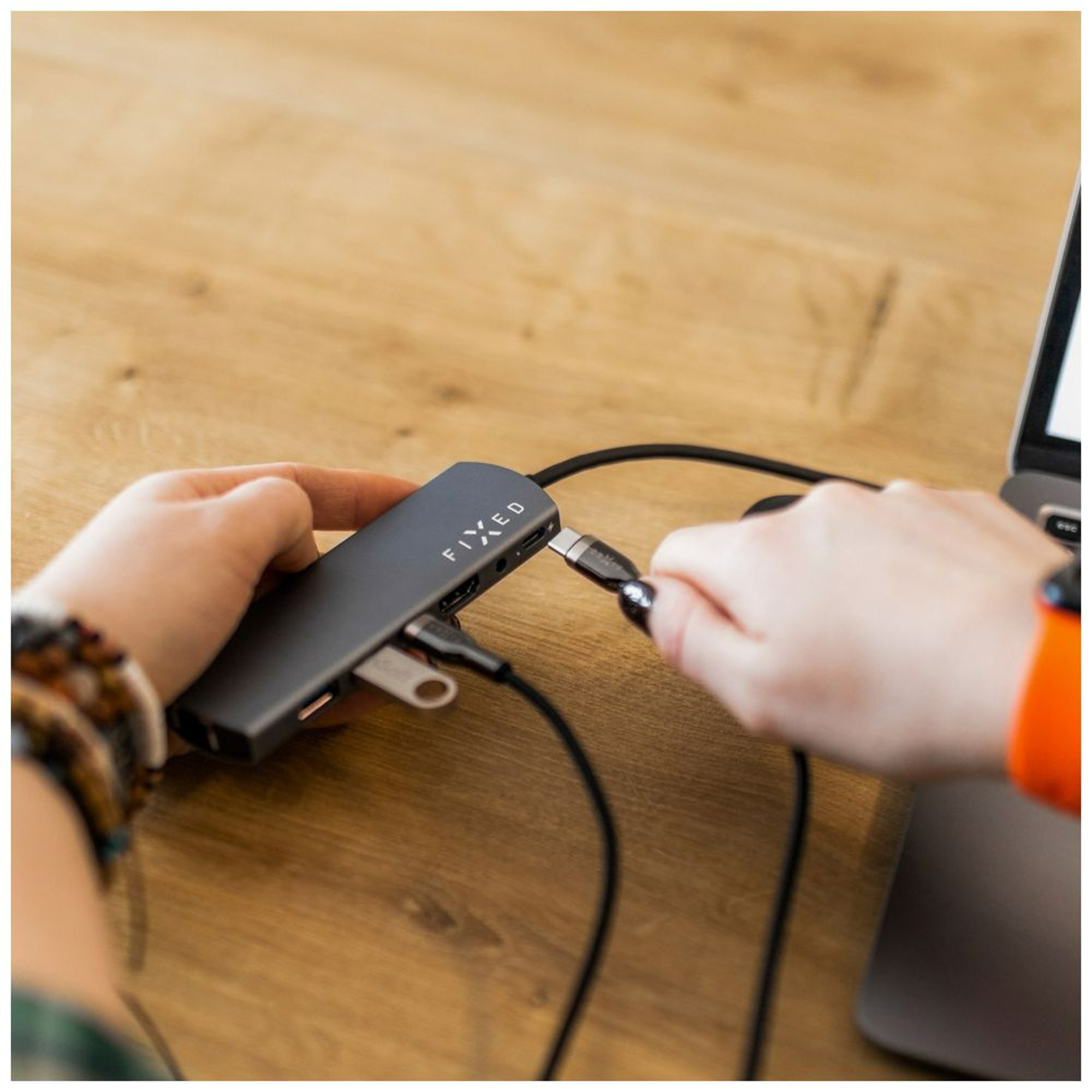 Person, die ein USB-C-Kabel in einen Hub einsteckt, der mit einem Laptop verbunden ist.