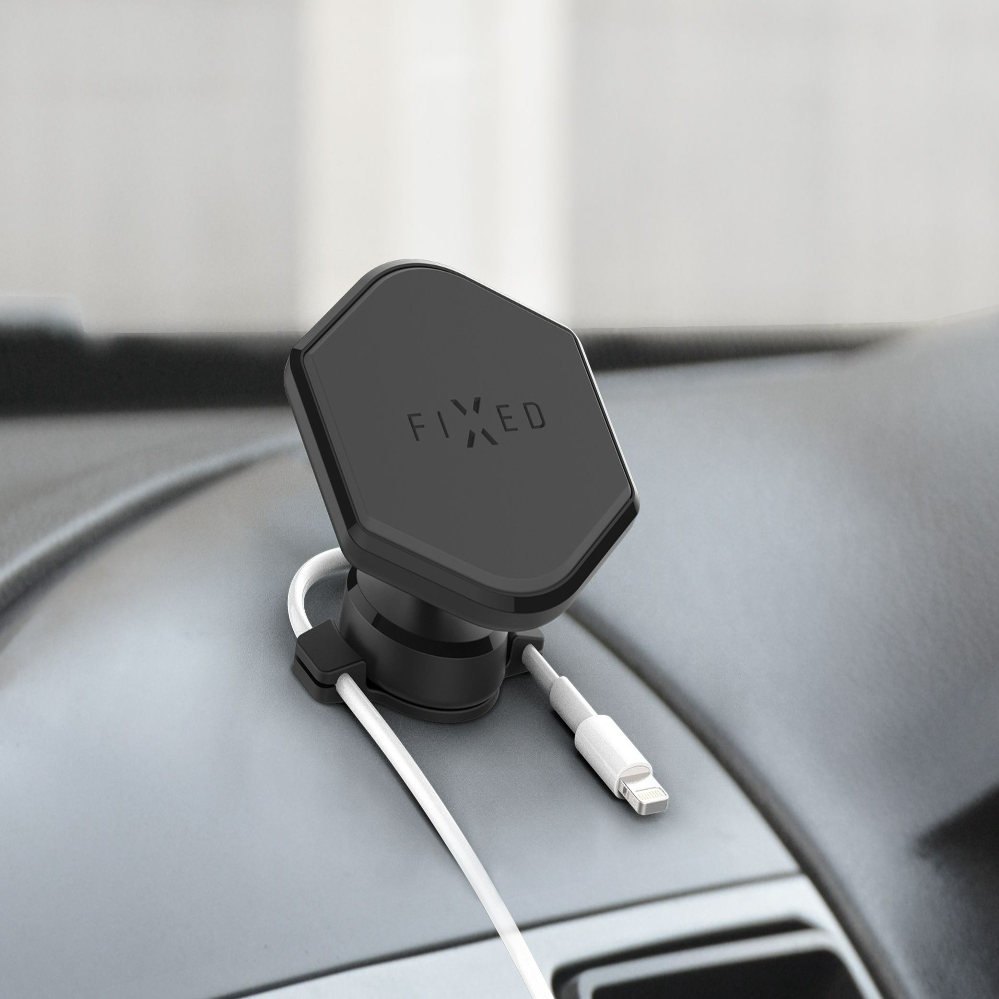Ein schwarzer Telefonhalter, der auf dem Armaturenbrett eines Autos montiert ist. Er hat ein weißes Ladekabel.