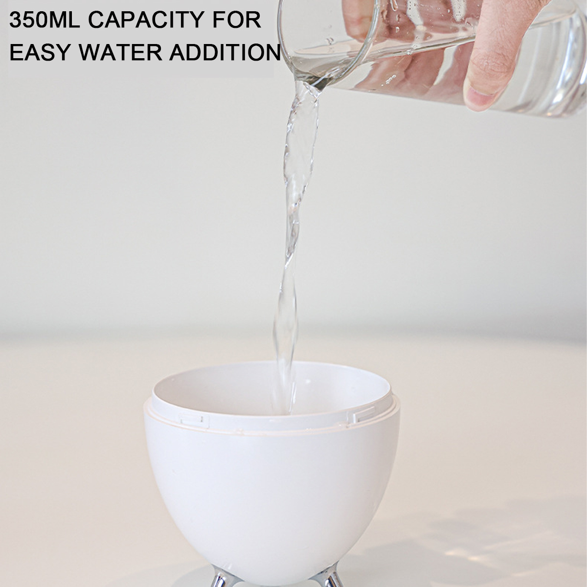 Eine Hand gießt Wasser in einen weißen, eiförmigen Luftbefeuchter. Text sagt 350 ml Kapazität für einfaches Hinzufügen von Wasser.
