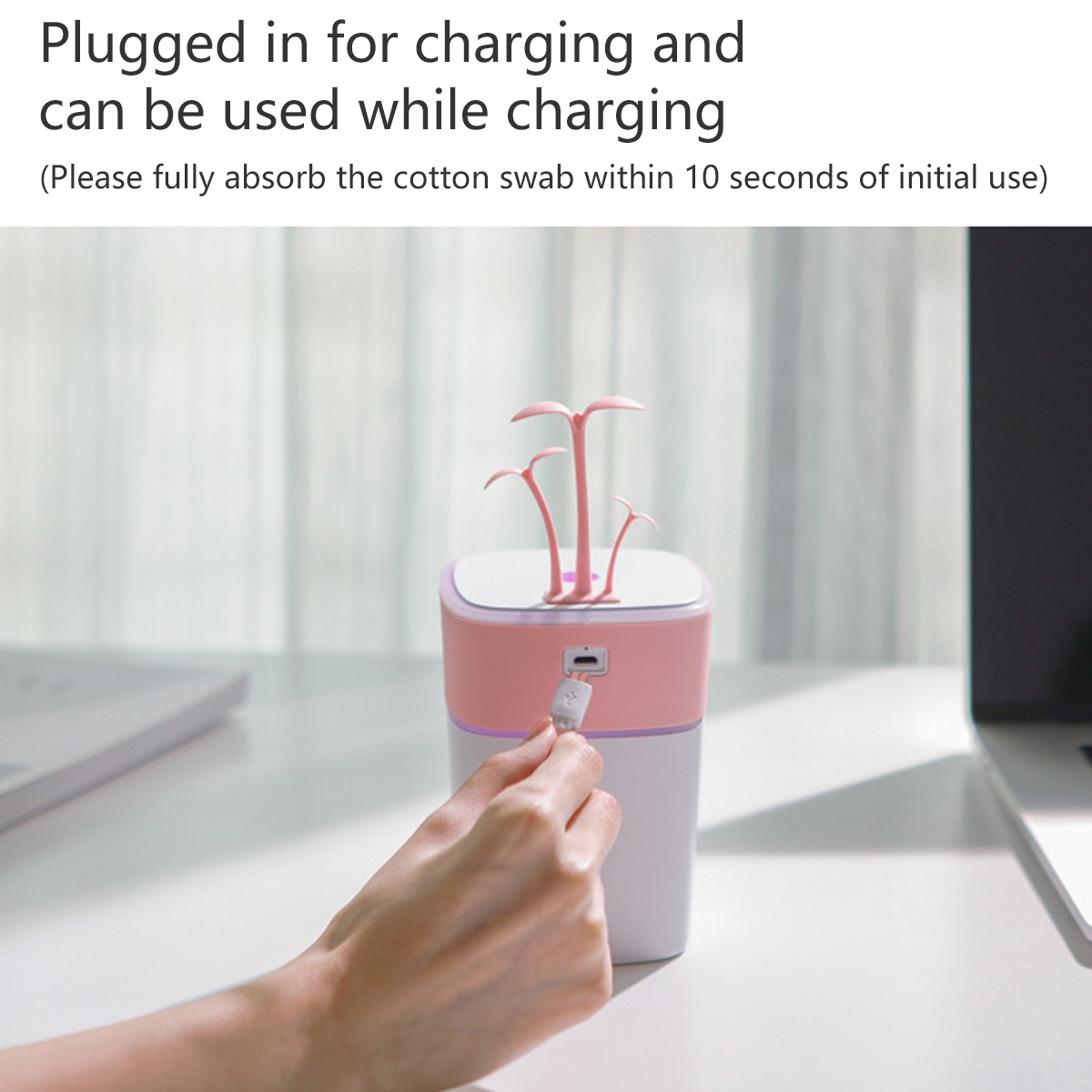 Kleiner rosa-weißer Luftbefeuchter mit USB-Anschluss, an einem USB-Kabel, auf einem Schreibtisch.