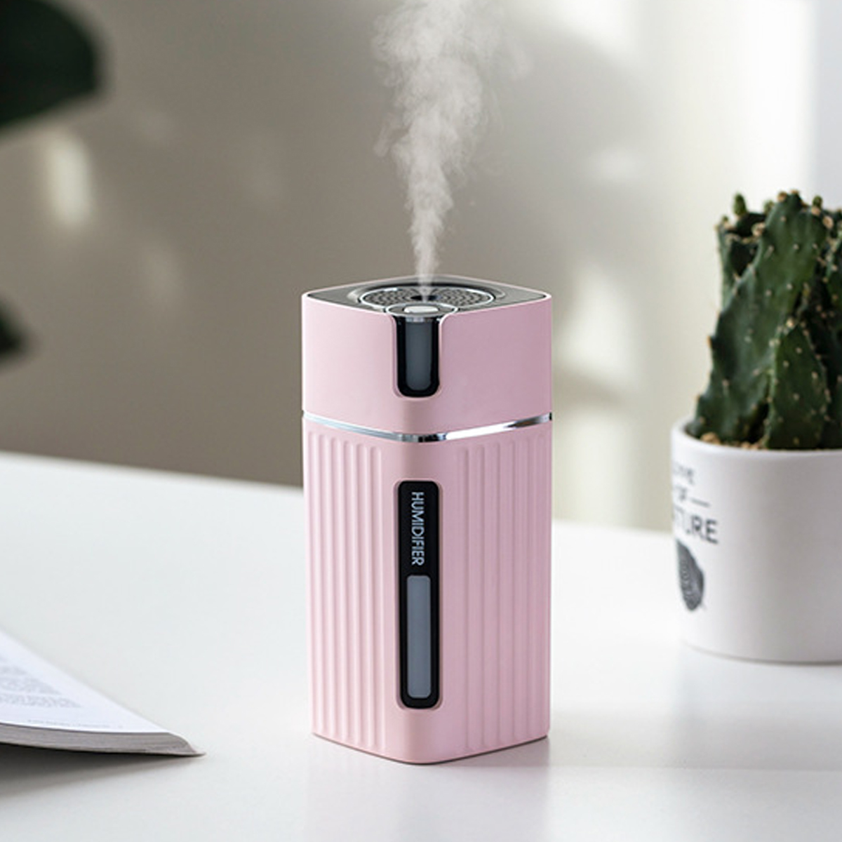 Ein rosa Luftbefeuchter mit dunklem Display, Dampf kommt oben heraus.