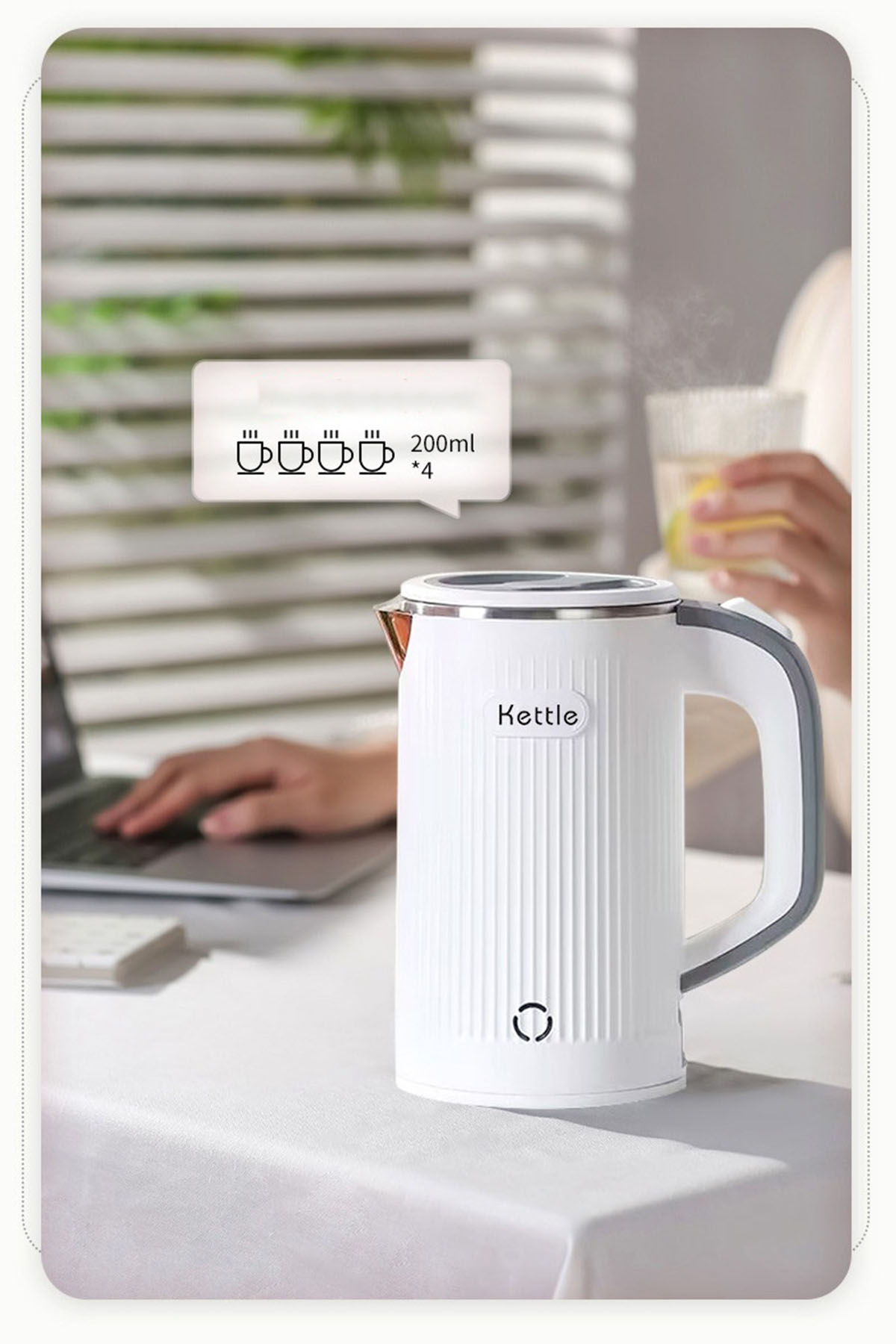 Weißer Wasserkocher mit Griff, beschriftet mit 'Kettle'. Eine Person arbeitet an einem Laptop, der Wasserkocher steht auf dem Tisch.
