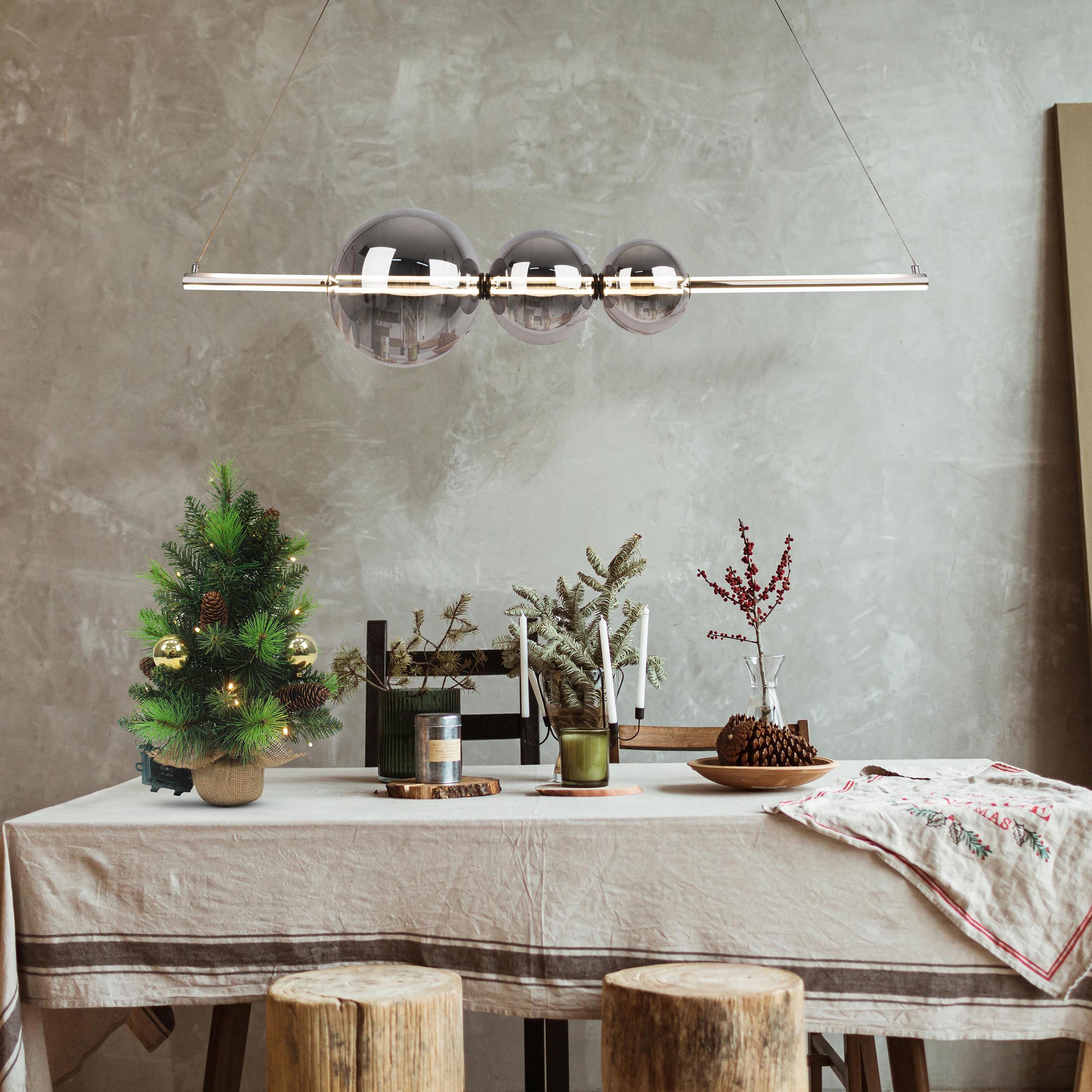 Ein Raum mit einem für das Abendessen gedeckten Tisch. Ein Weihnachtsbaum, Kerzen und ein Kronleuchter sind sichtbar.