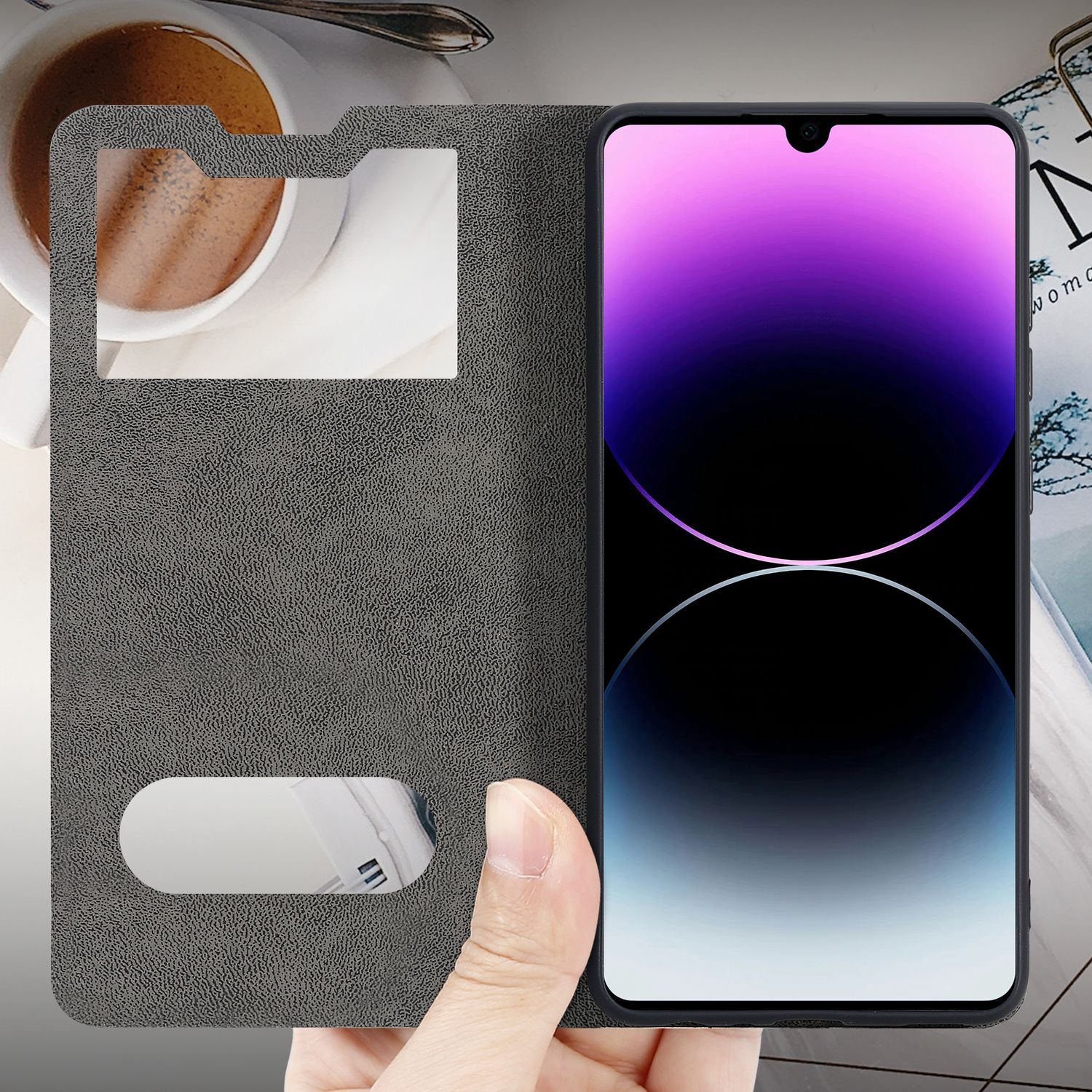 Mano che tiene aperta una custodia per telefono, che mostra lo schermo dello smartphone. Tazza di caffè sullo sfondo.