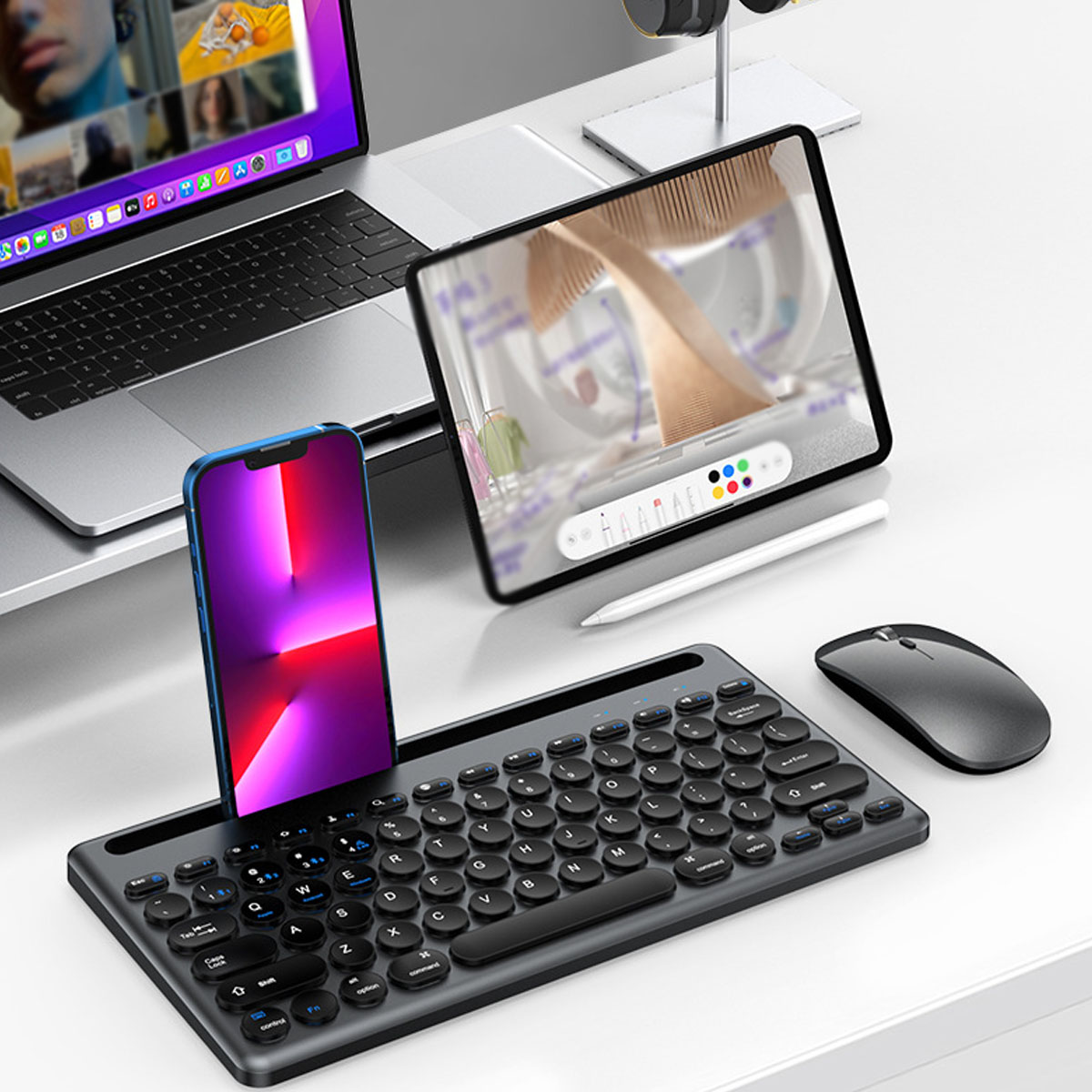 Laptop, Telefon und Tablet auf einem Schreibtisch mit Tastatur und Maus.