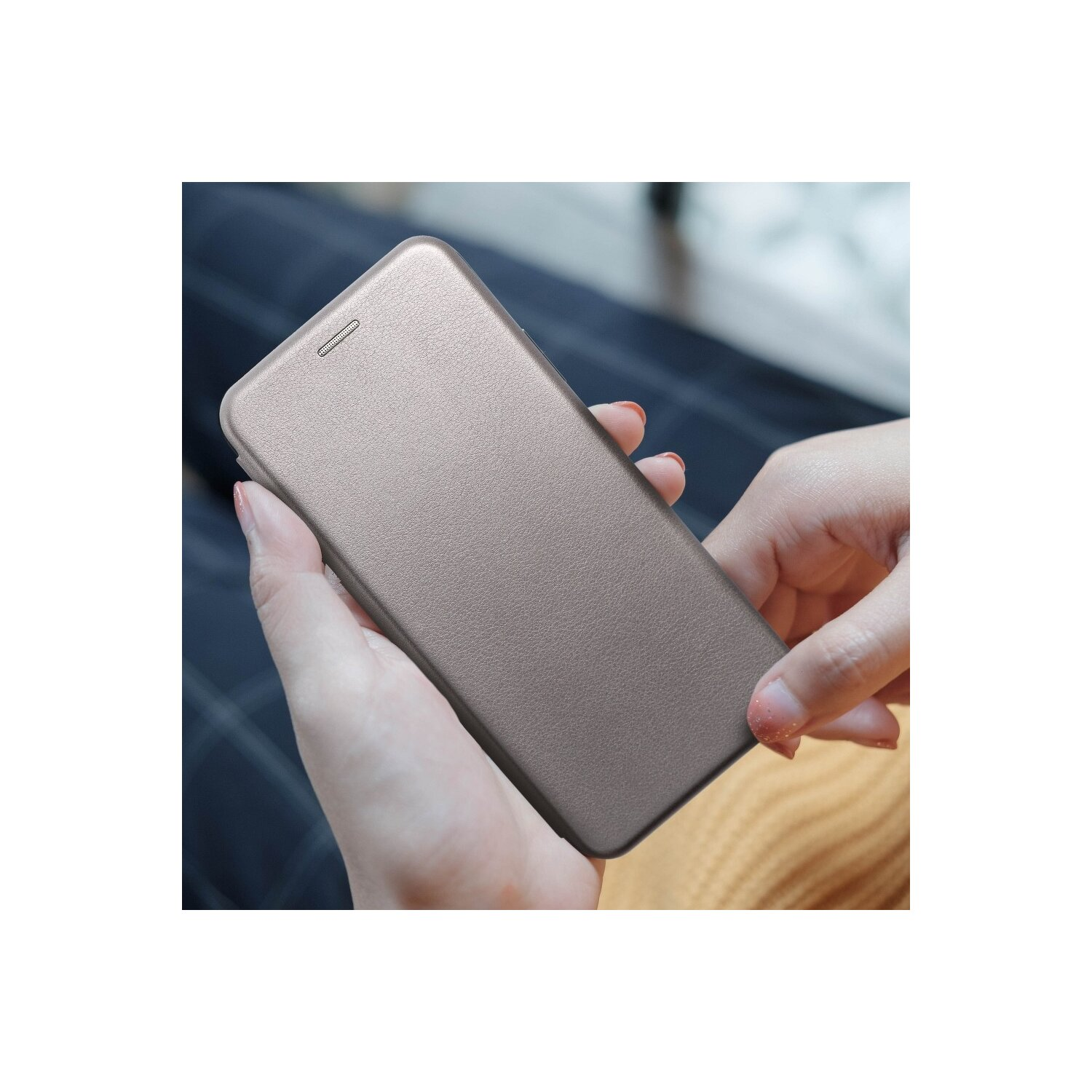 Hände halten ein goldenes Telefon, zeigen die Rückseite. Das Telefon ist in einer Hülle. Der Hintergrund ist unscharf.