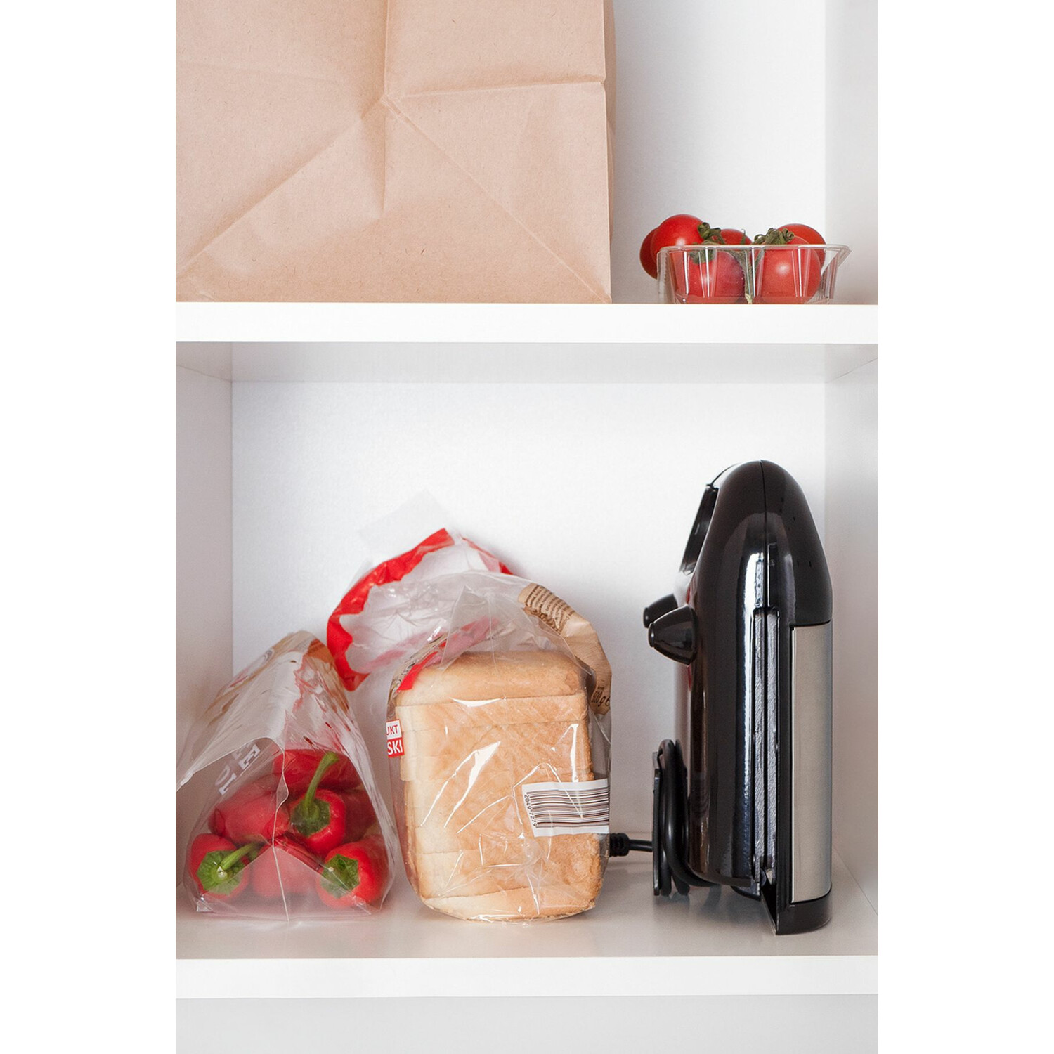 Eine Speisekammer mit Brot, Tomaten in einer Schüssel und einem Toaster. Die Regale sind weiß.