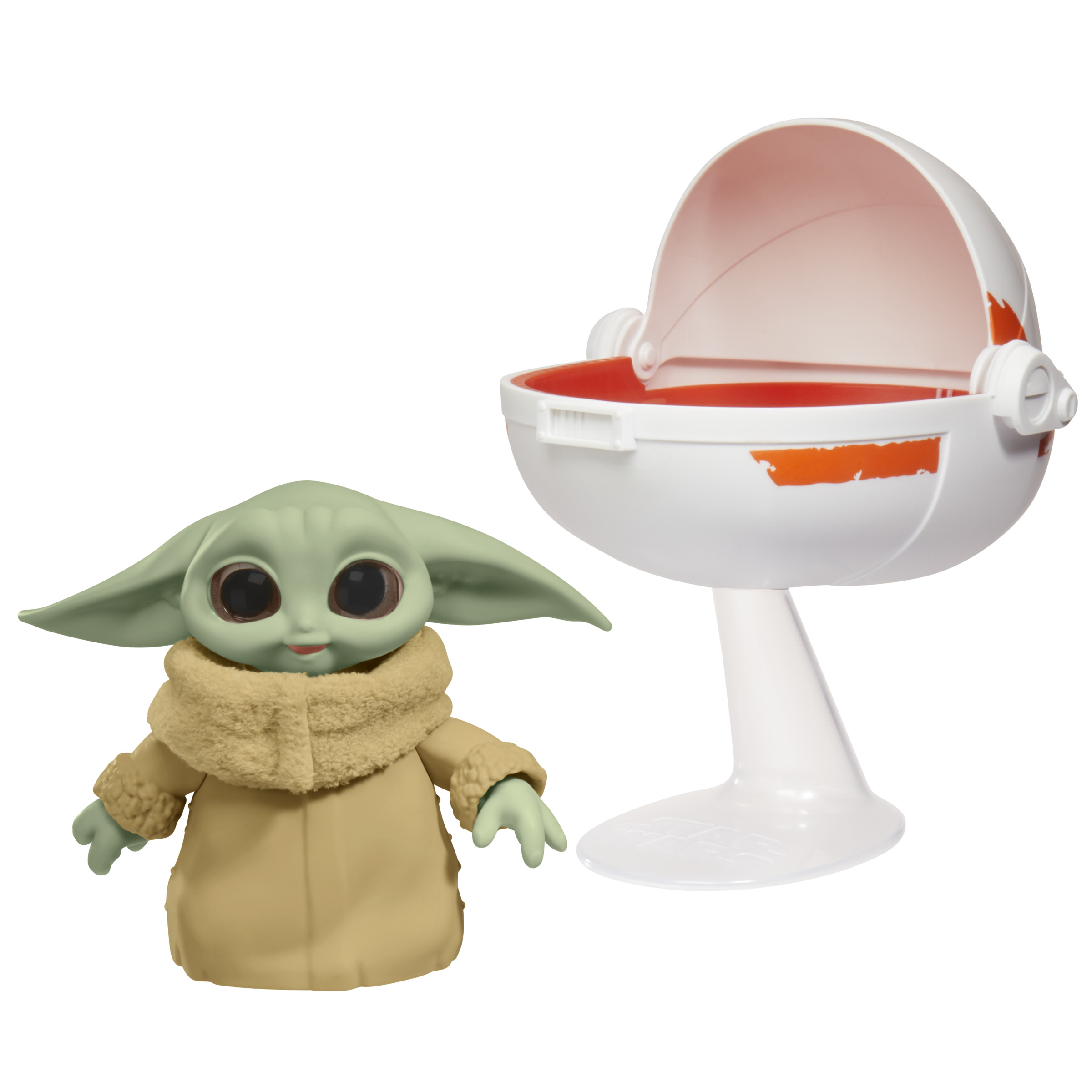 Grogu, el bebé Yoda, con un portabebés de juguete. Grogu tiene piel verde y ojos grandes.