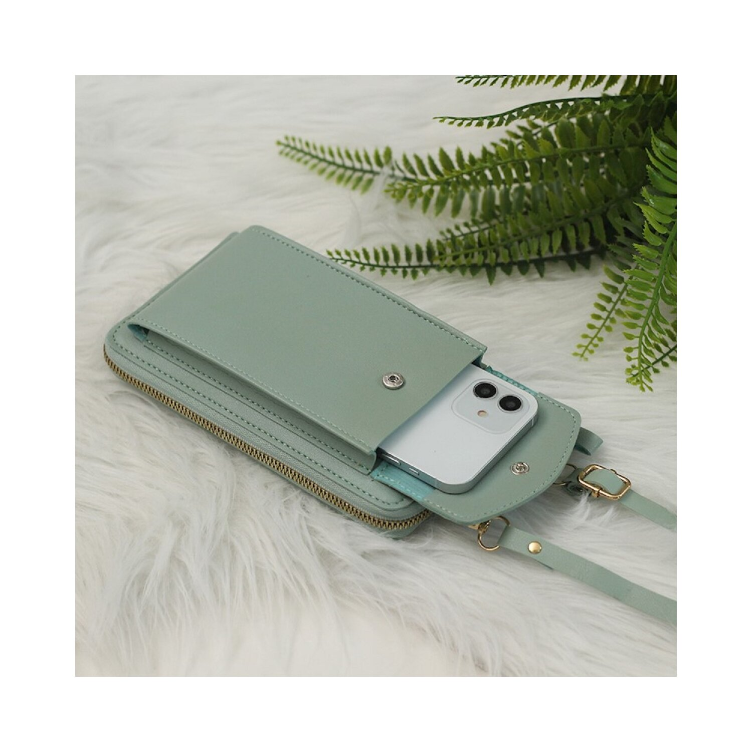 Minzgrüne Telefontasche mit Telefon, auf weißem Pelzhintergrund.