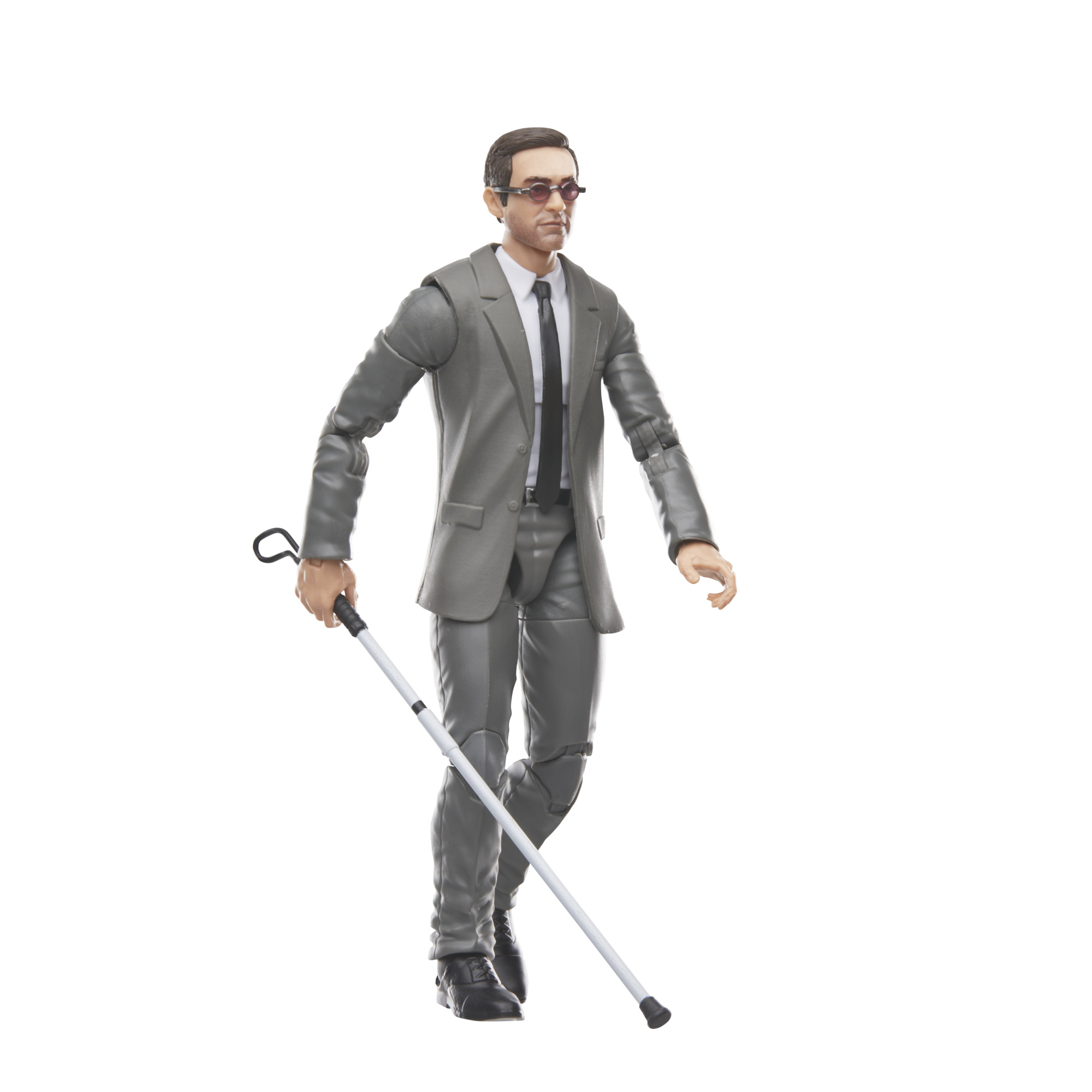 Una figura con traje gris con gafas de sol, sosteniendo un bastón blanco. Está caminando.