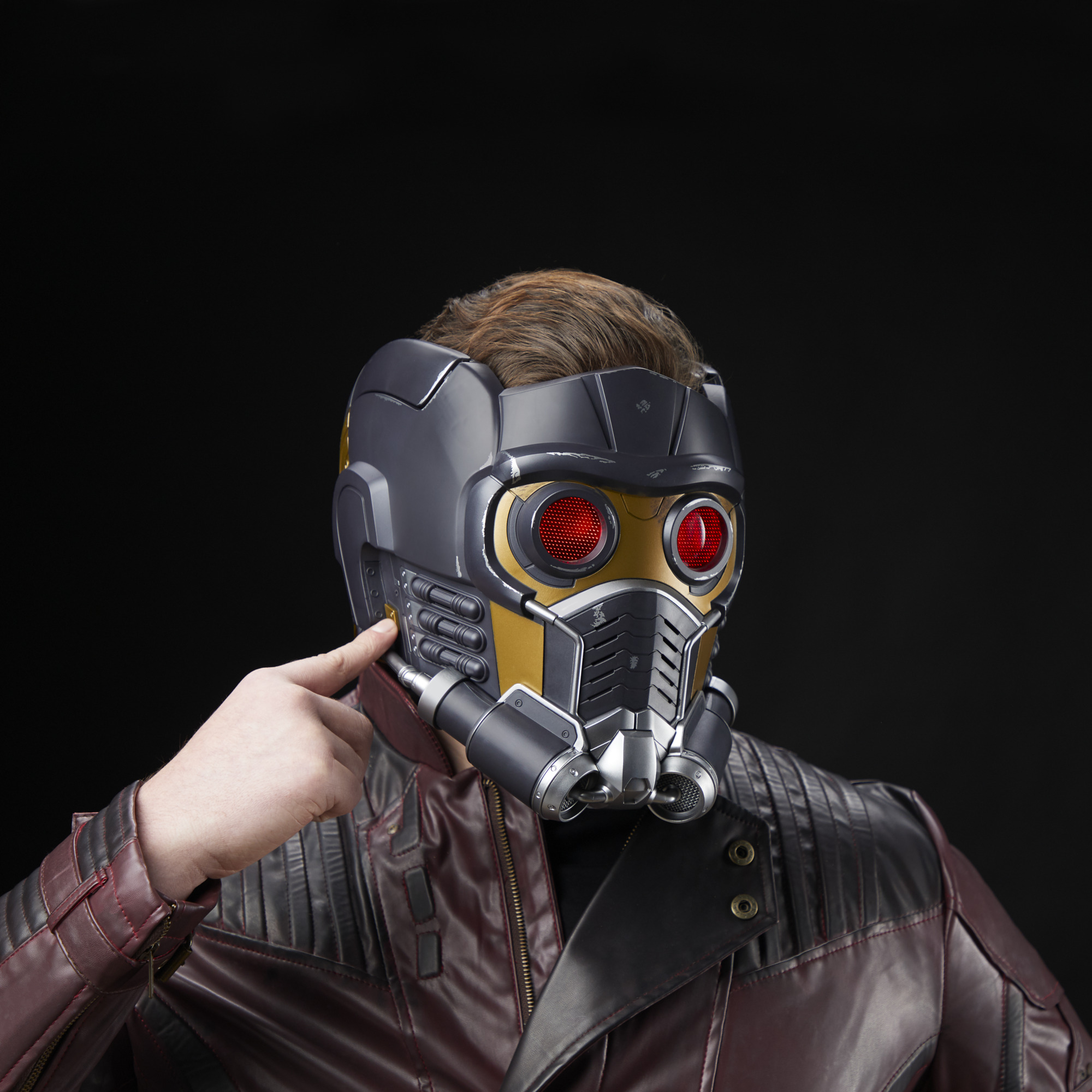 Persona usando casco de Star-Lord, con ojos rojos y placa dorada, sobre fondo negro.