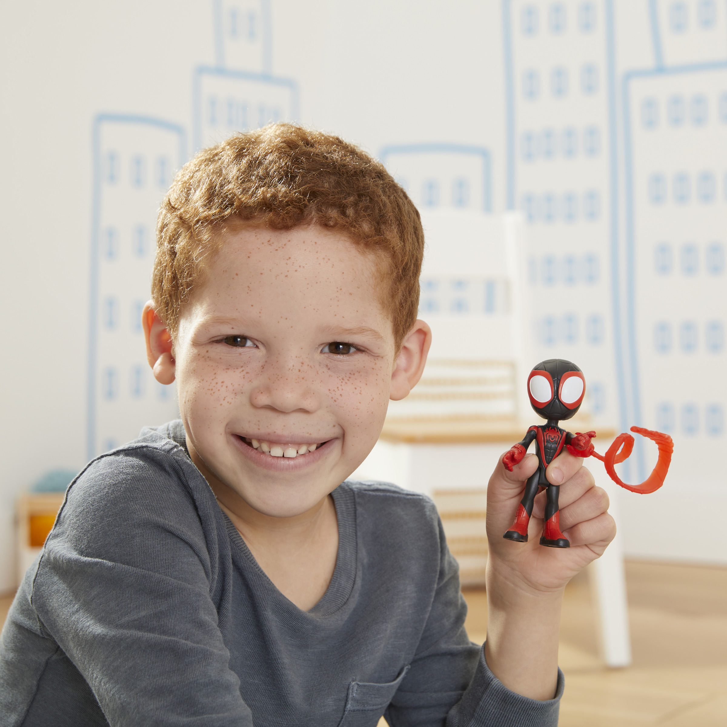 Un niño sosteniendo una figura de acción de Spider-Man. La figura es negra y roja.