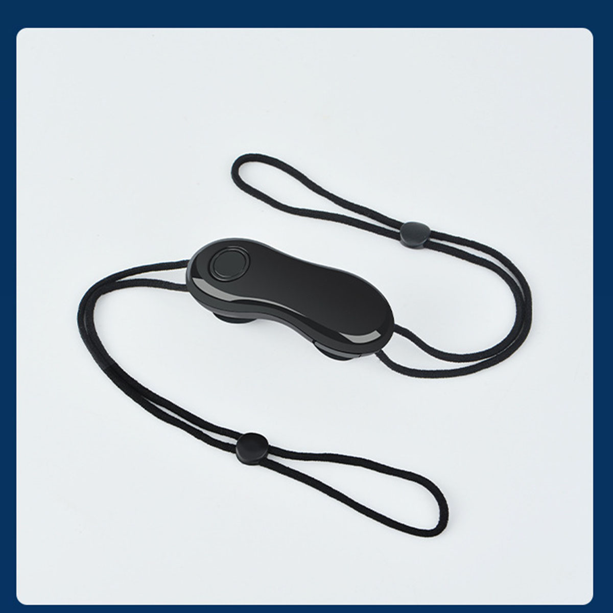 Eine schwarze Fernbedienung mit Nackengurt, die auf einer weißen Oberfläche liegt.