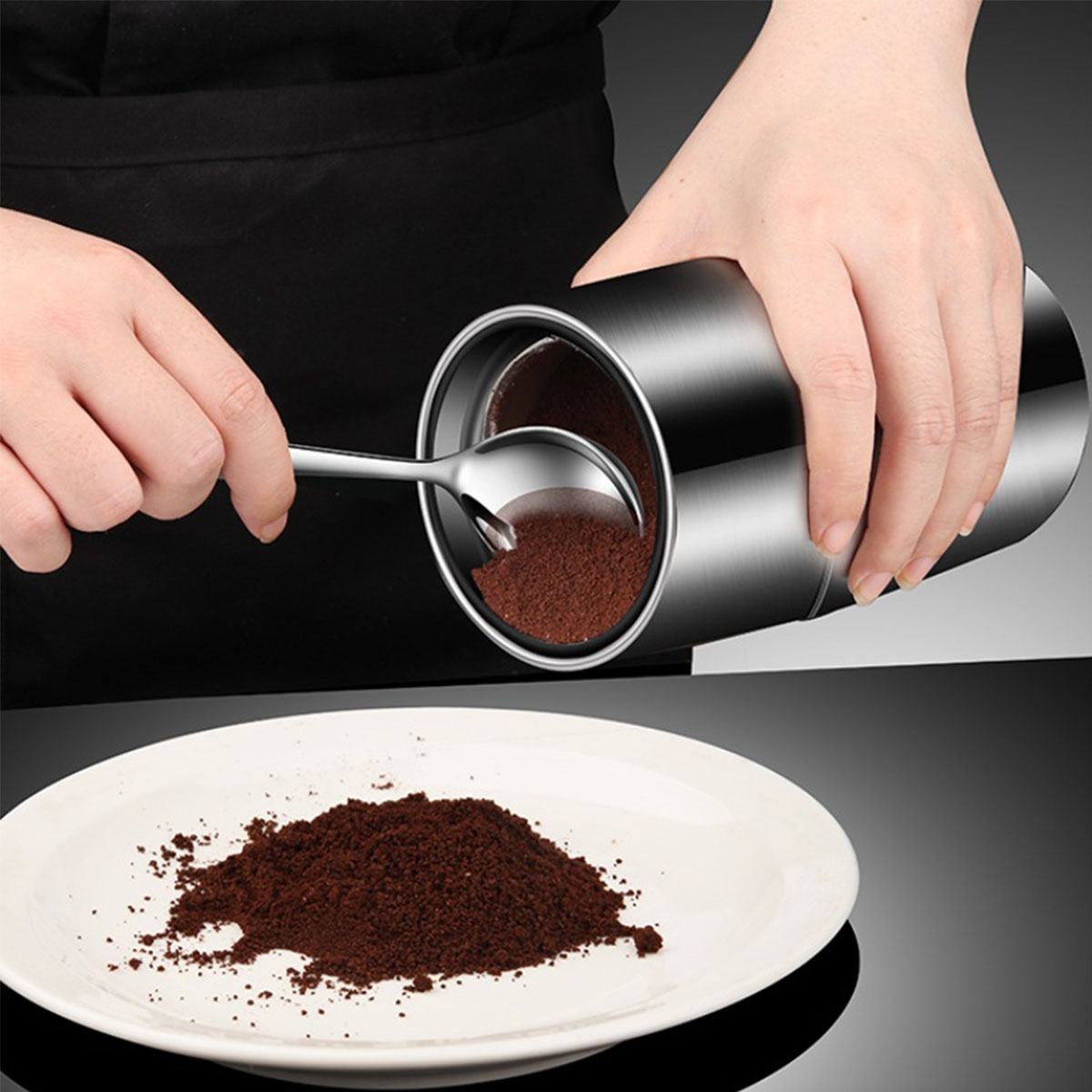 Eine Person schöpft Kaffeepulver aus einem Behälter auf einen weißen Teller. Ein Haufen Pulver ist sichtbar.