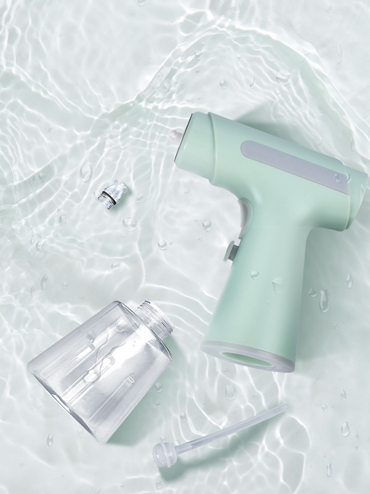 Ein Hand-Sprühgerät und ein klarer Plastikbehälter auf einer Wasseroberfläche. Das Gerät ist mintgrün.