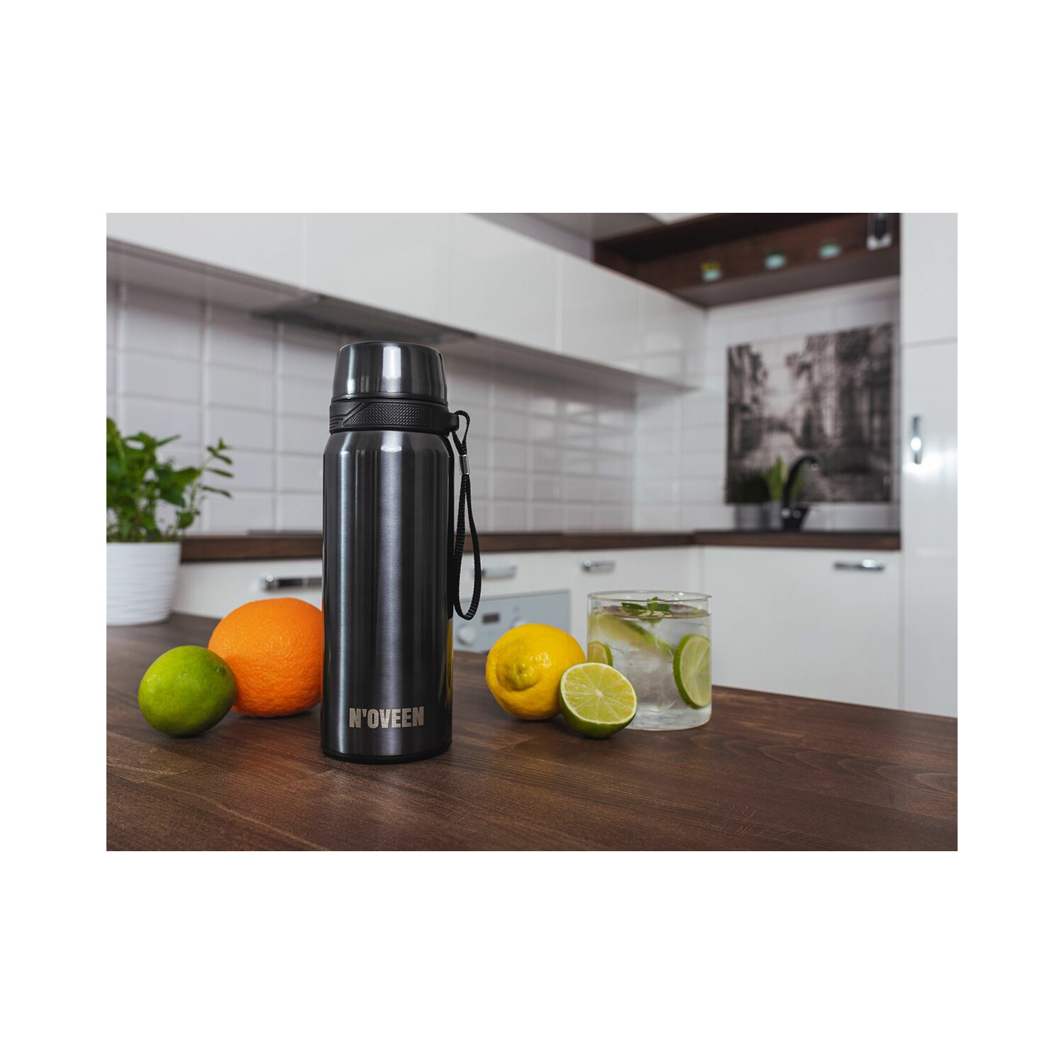 Schwarze Wasserflasche und Früchte mit einem Glas Wasser auf einem Holztisch.