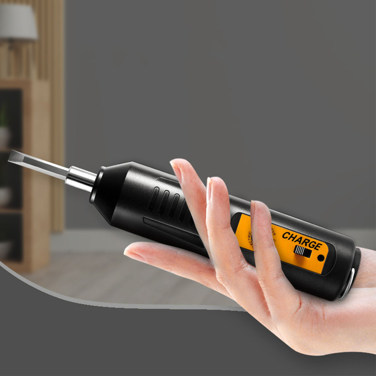 Hand hält einen schwarzen elektrischen Schraubendreher mit gelbem 'CHARGE'-Aufkleber.