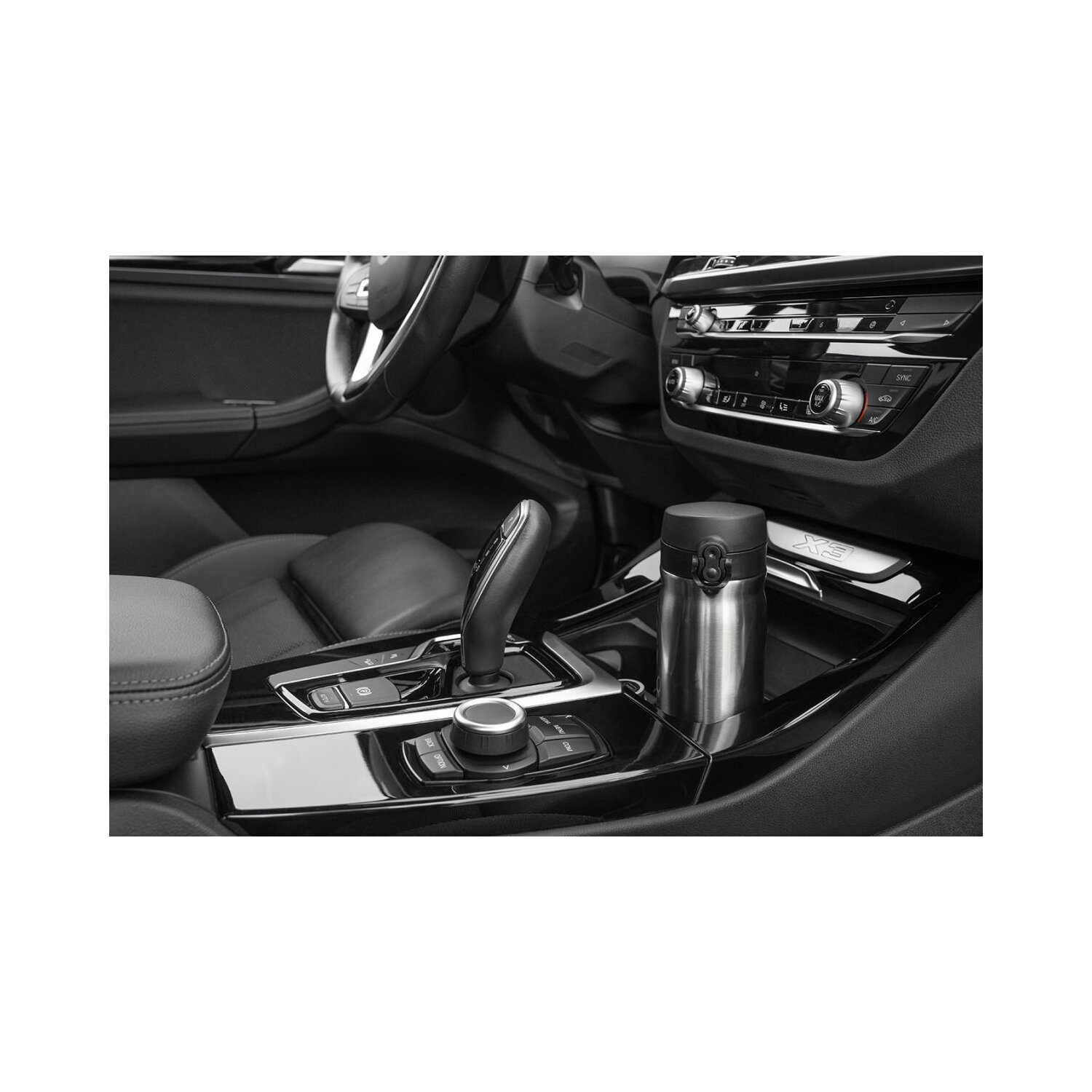 Ein Edelstahl-Isolierbecher im Getränkehalter eines Autos, schwarze Innenausstattung.