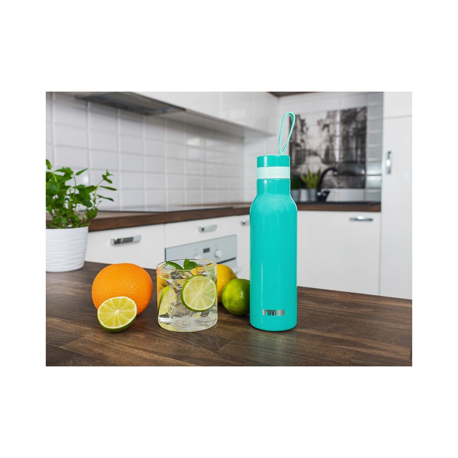 Türkisgrüne Wasserflasche mit Früchten und einem Mojito-Glas auf einem Holztisch.