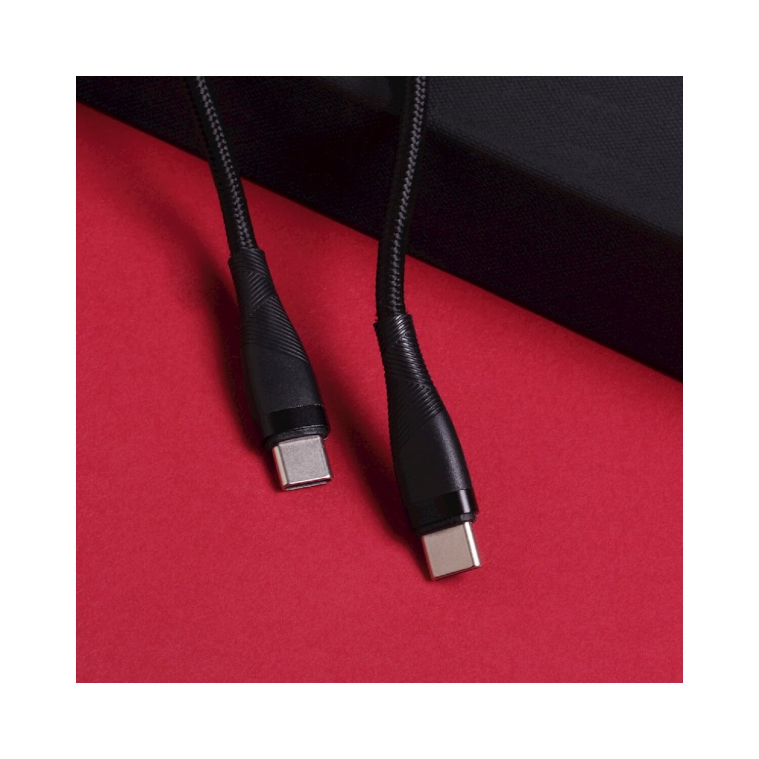 Zwei schwarze USB-C-Kabel auf roter Oberfläche nebeneinander, die Kabelenden zeigend.