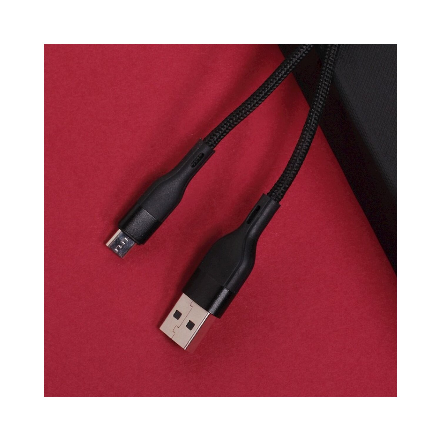 Schwarzes USB-Kabel mit USB-A- und Micro-USB-Anschluss auf rotem Hintergrund. Das Kabel ist geflochten.