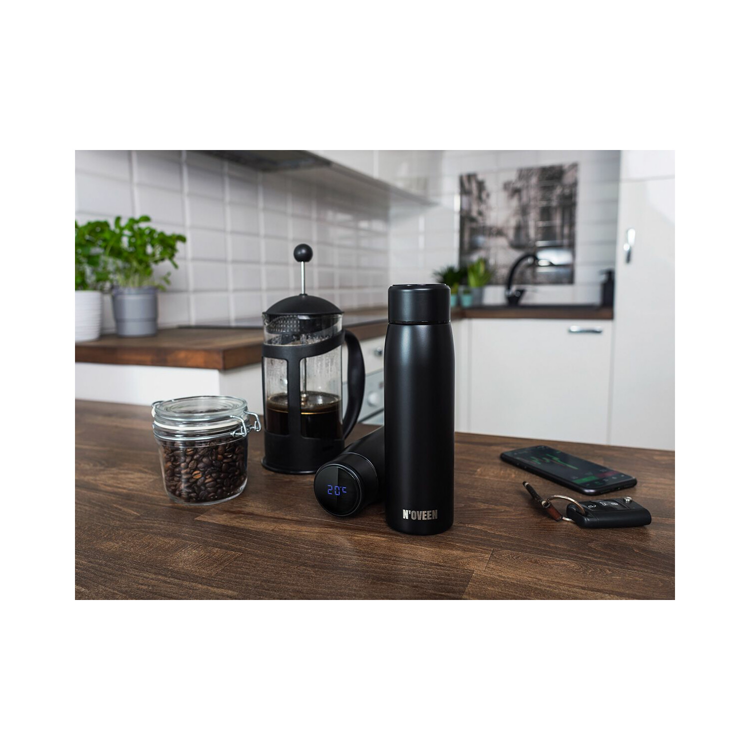 Schwarze Wasserflasche, Kaffeemaschine, Kaffeebohnen und Telefon auf einer Holztheke vor einer Küche.