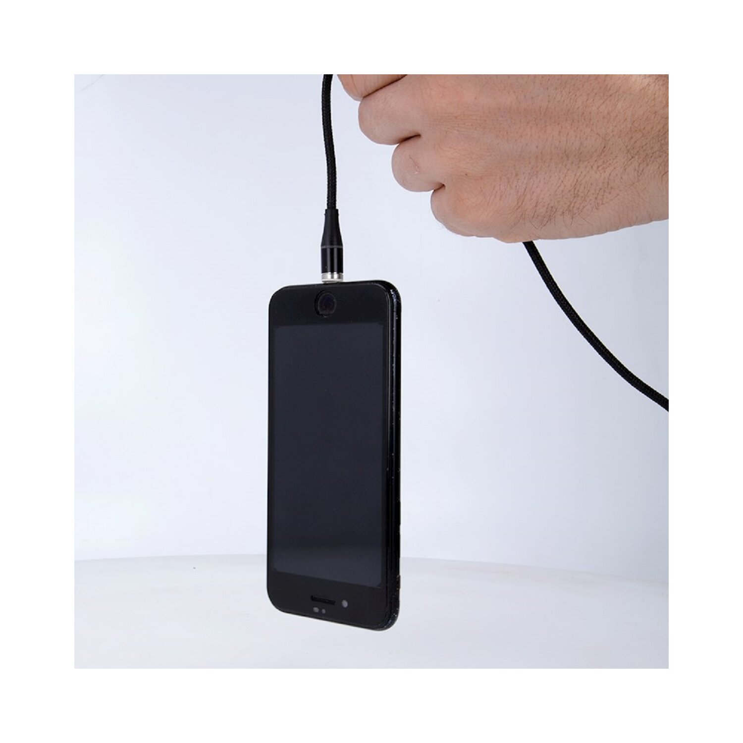 Eine Hand hält ein schwarzes Telefon, das mit einem schwarzen Kabel verbunden ist. Der Hintergrund ist weiß.