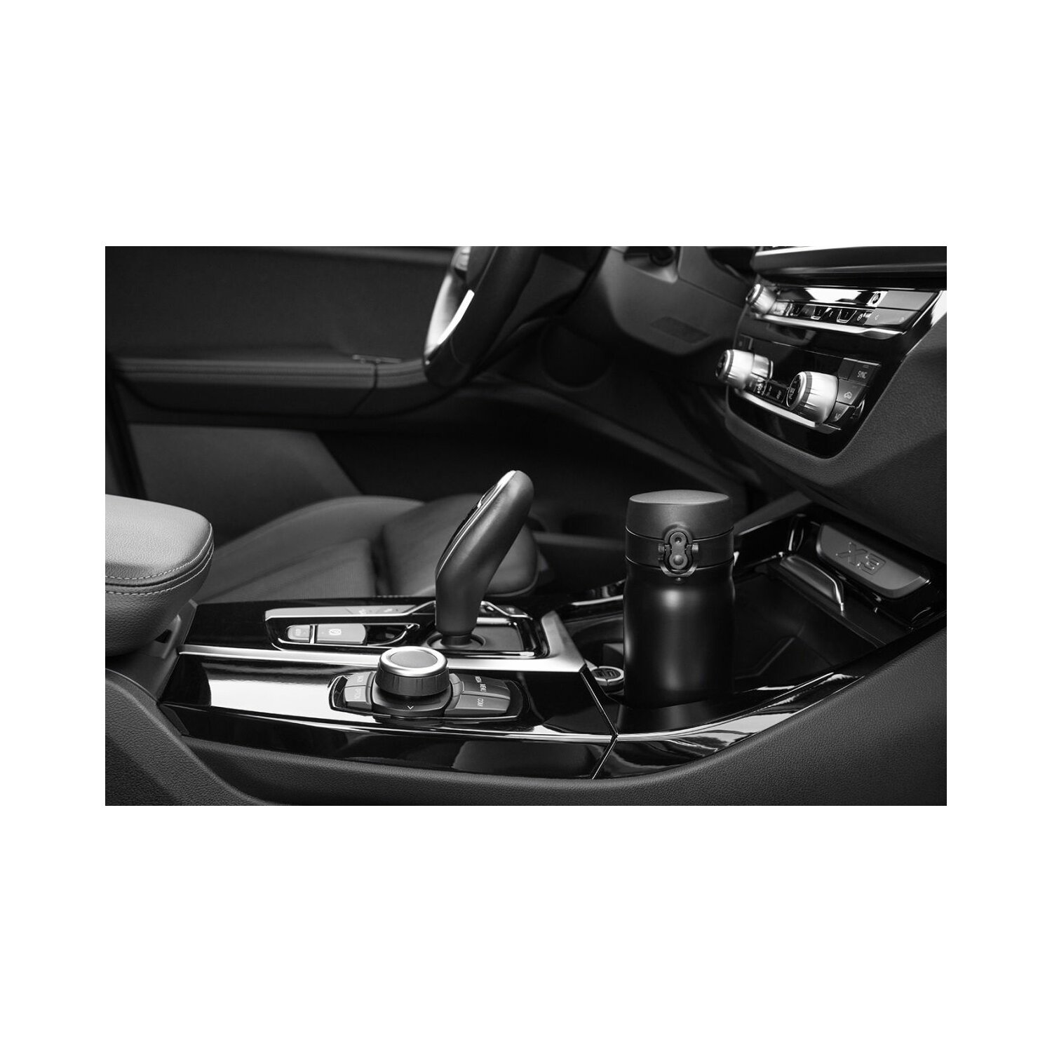 Ein schwarzer Becher in der Konsole eines Autos, mit Gangschaltung und Armaturenbrett.