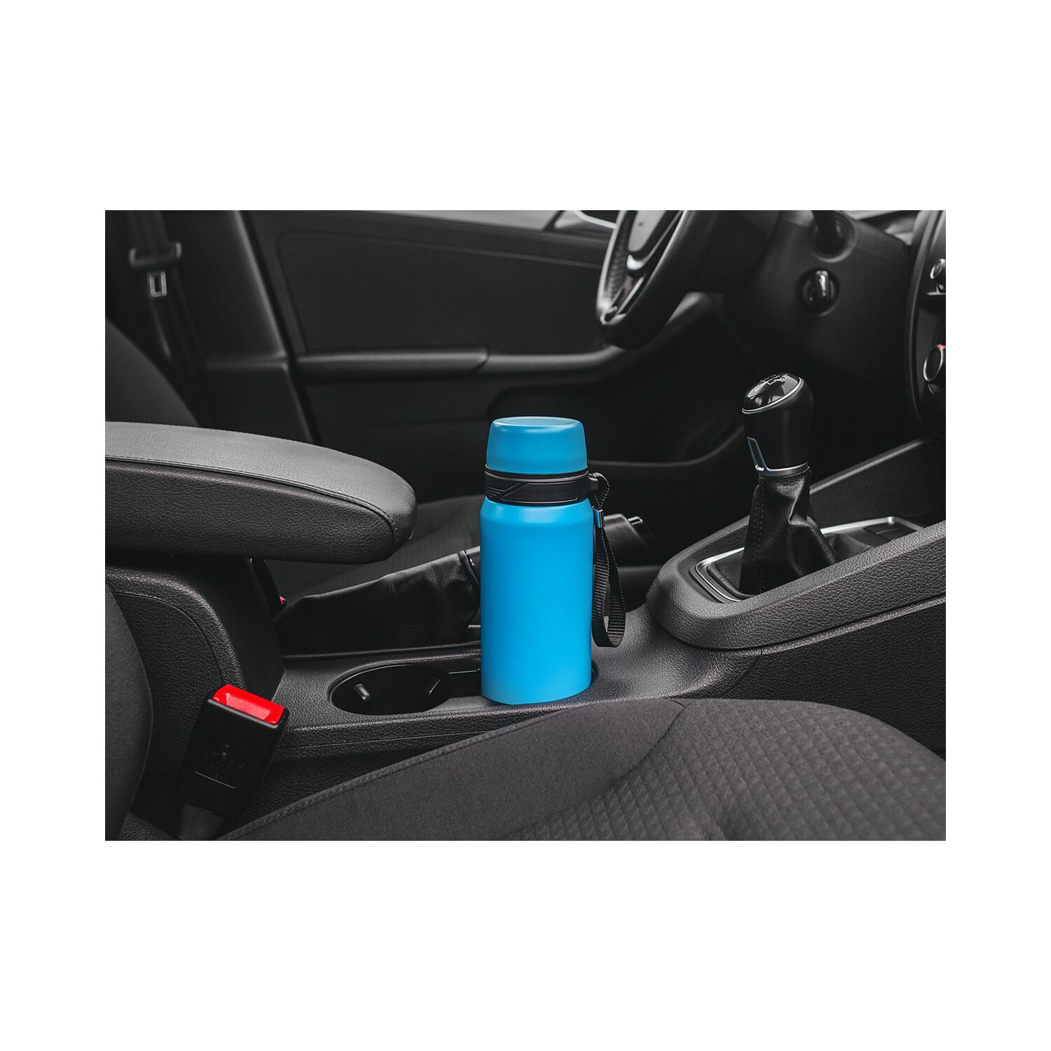 Blaue Wasserflasche in der Mittelkonsole eines Autos. Der Innenraum des Autos ist schwarz.