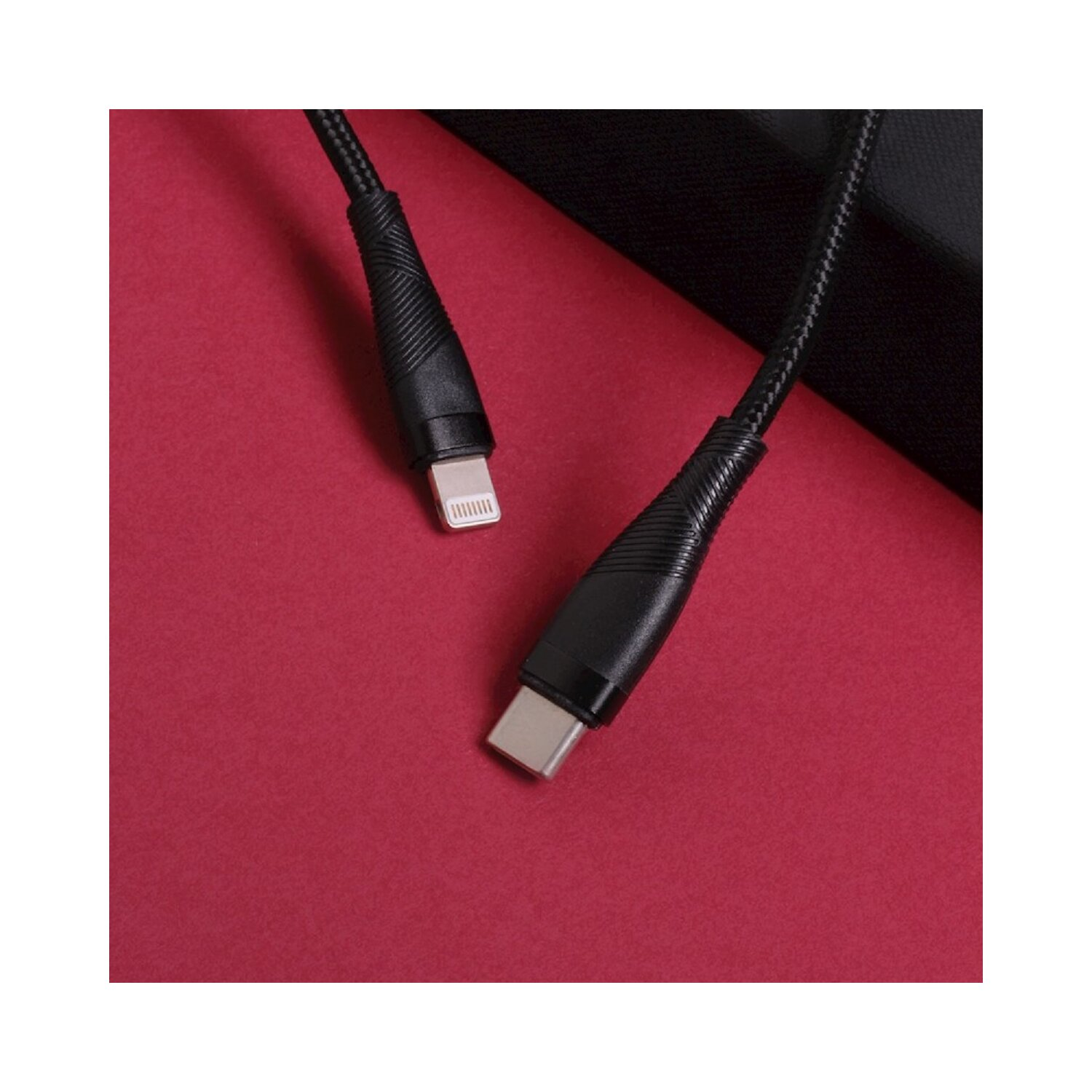 Ein schwarzes Ladekabel mit USB-C- und Lightning-Anschluss auf rotem Hintergrund.