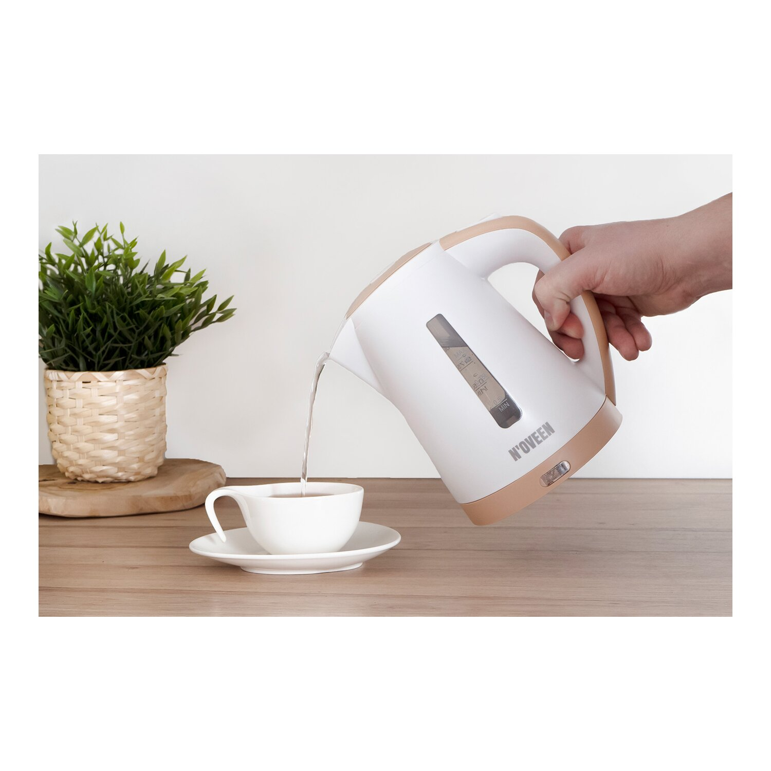 Biały czajnik nalewa wodę do białej filiżanki na drewnianym stole.