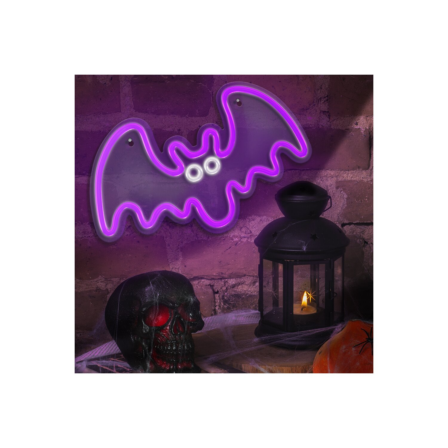 Halloween-Dekoration: lila Neonfledermaus, Totenkopf und Laterne an einer Backsteinmauer.