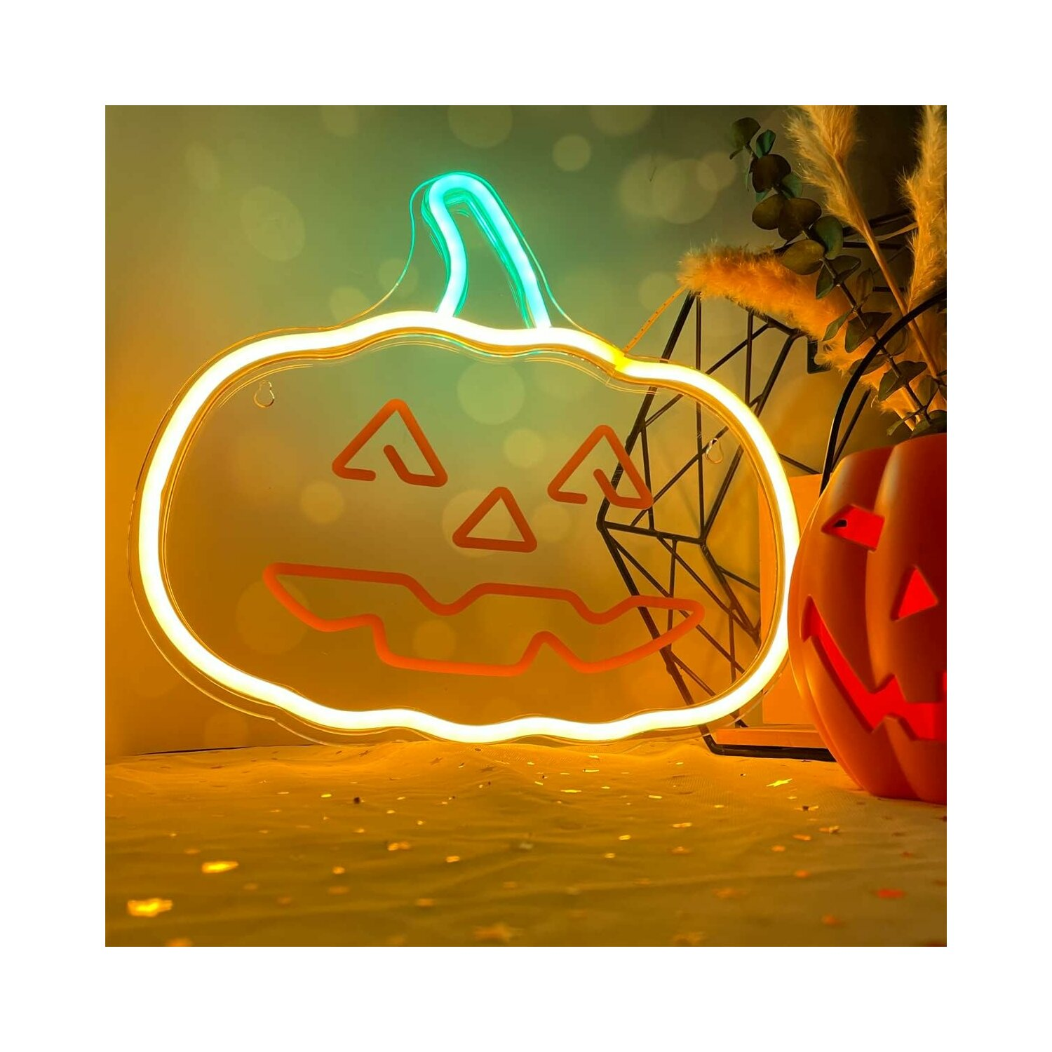 Ein Neon-Kürbis mit einem orangefarbenen Gesicht. Er steht vor einem Tisch. Zwei Kürbisse sind rechts.