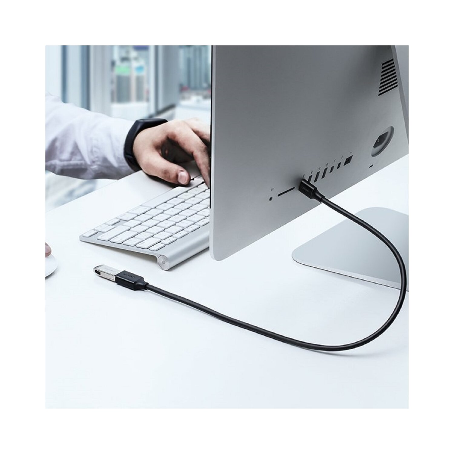 Osoba podłącza czarny kabel USB-C do tyłu komputera.