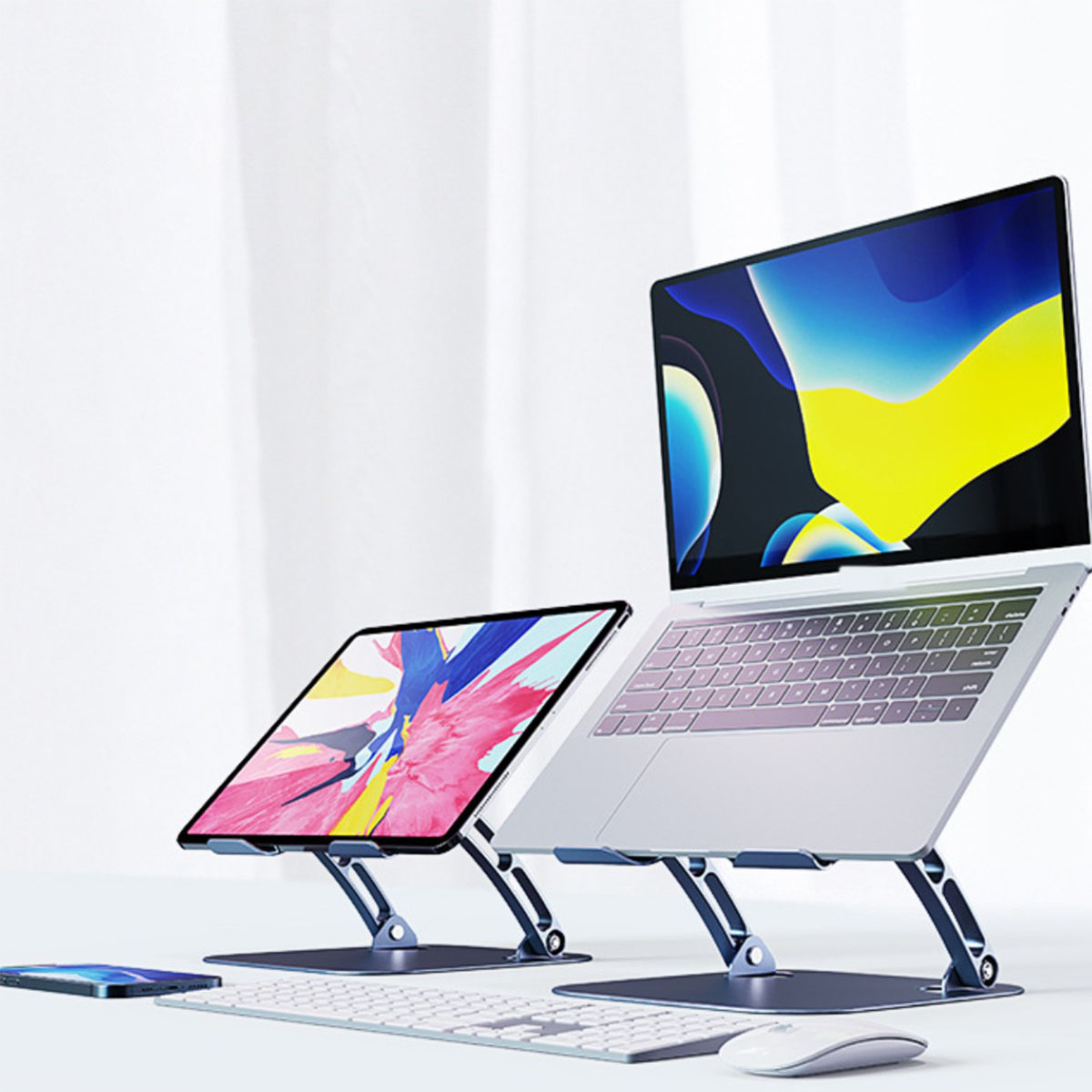 Laptop und Tablet auf Ständern. Tastatur und Maus auf weißer Oberfläche, weißer Hintergrund.