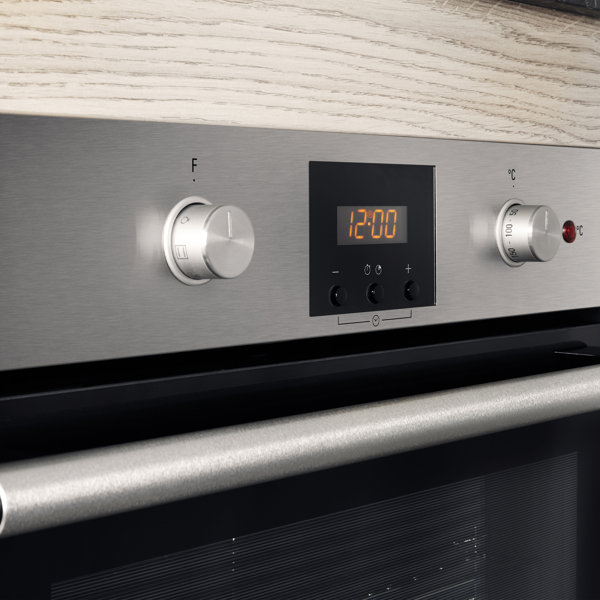 Backofen-Bedienfeld mit Digitalanzeige, die 12:00 anzeigt, und Reglern für Temperatur und Funktion.