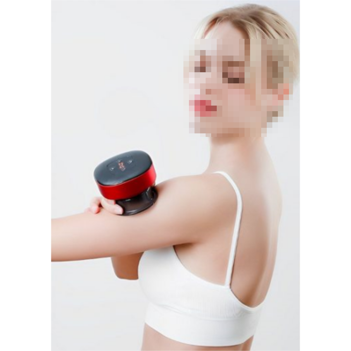 Mujer con un dispositivo de masaje en el brazo, top blanco y fondo borroso.