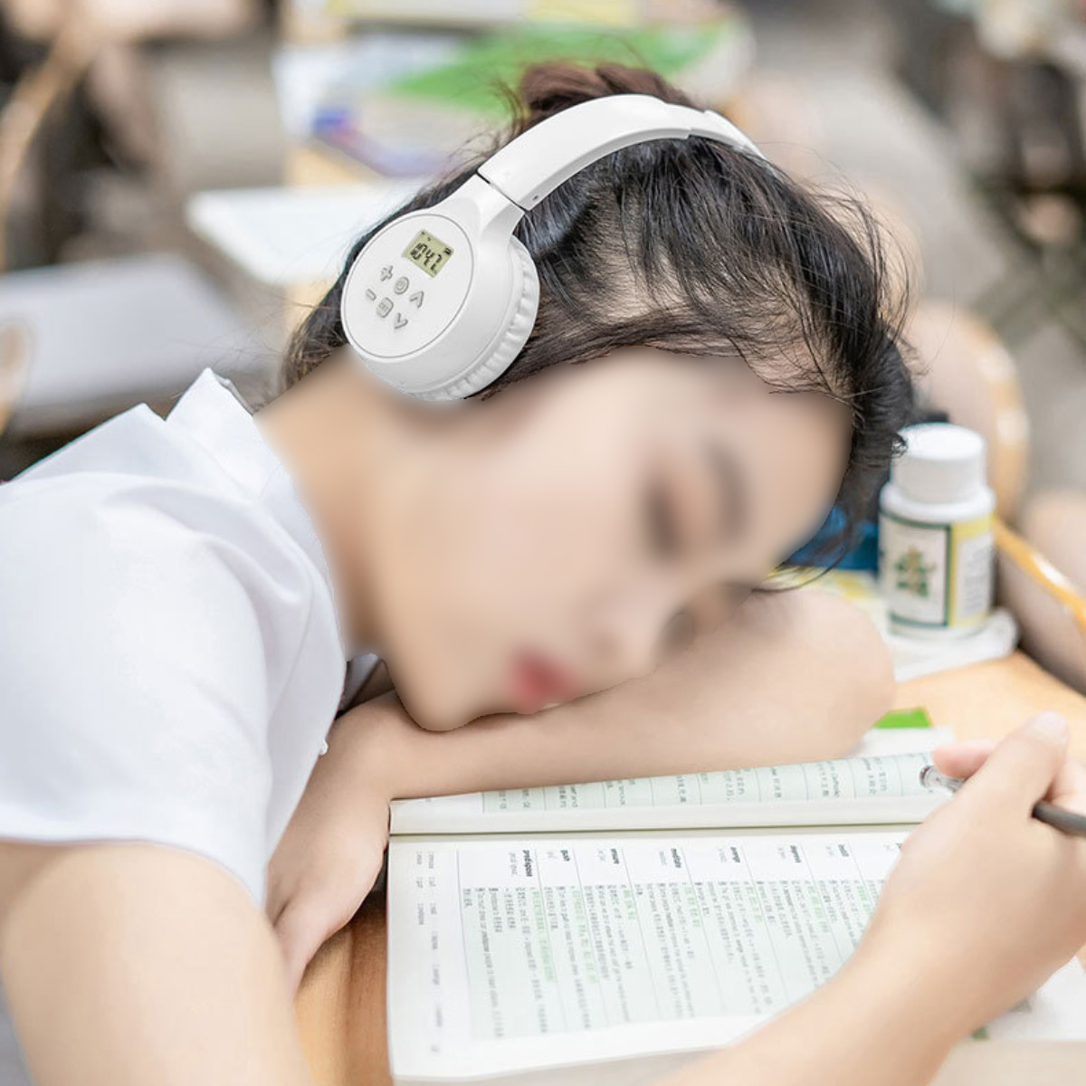 Eine Frau mit weißen Kopfhörern lehnt an einem Schreibtisch mit Buch und Stift vor sich.