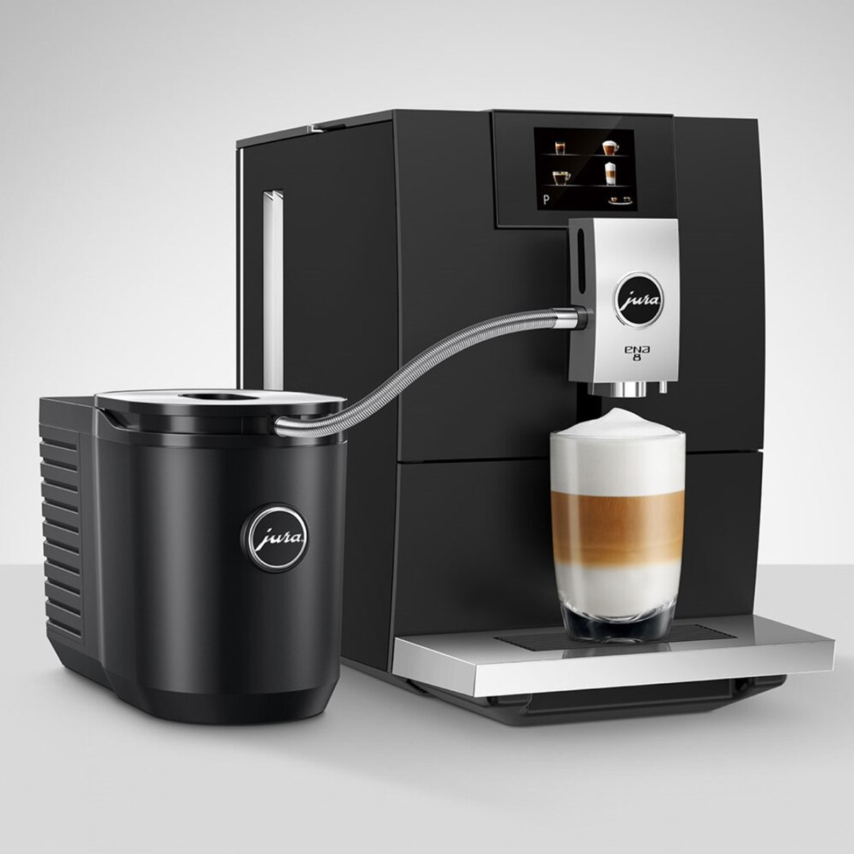 Una cafetera Jura ENA 8 negra con un recipiente para leche, una taza con espuma de leche.