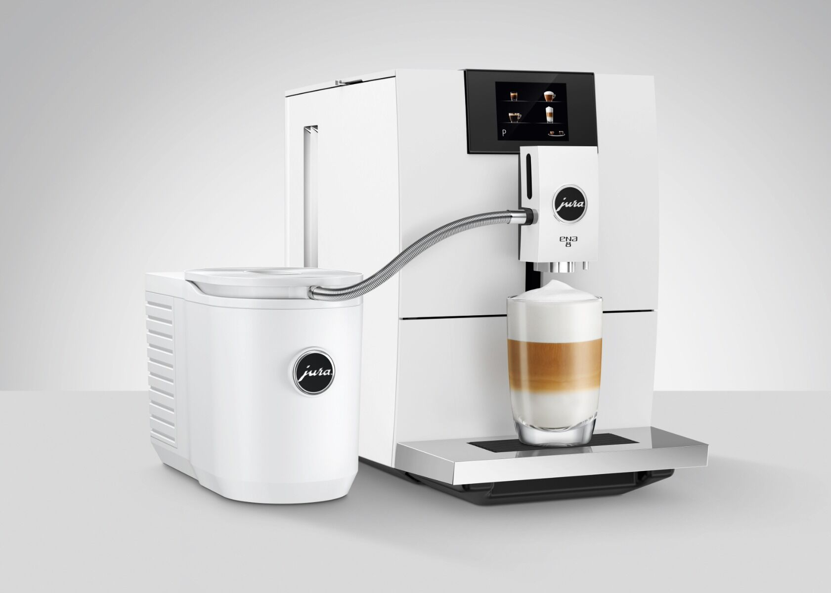 Una macchina da caffè Jura E8 bianca, con un contenitore per il latte e un bicchiere di latte macchiato.