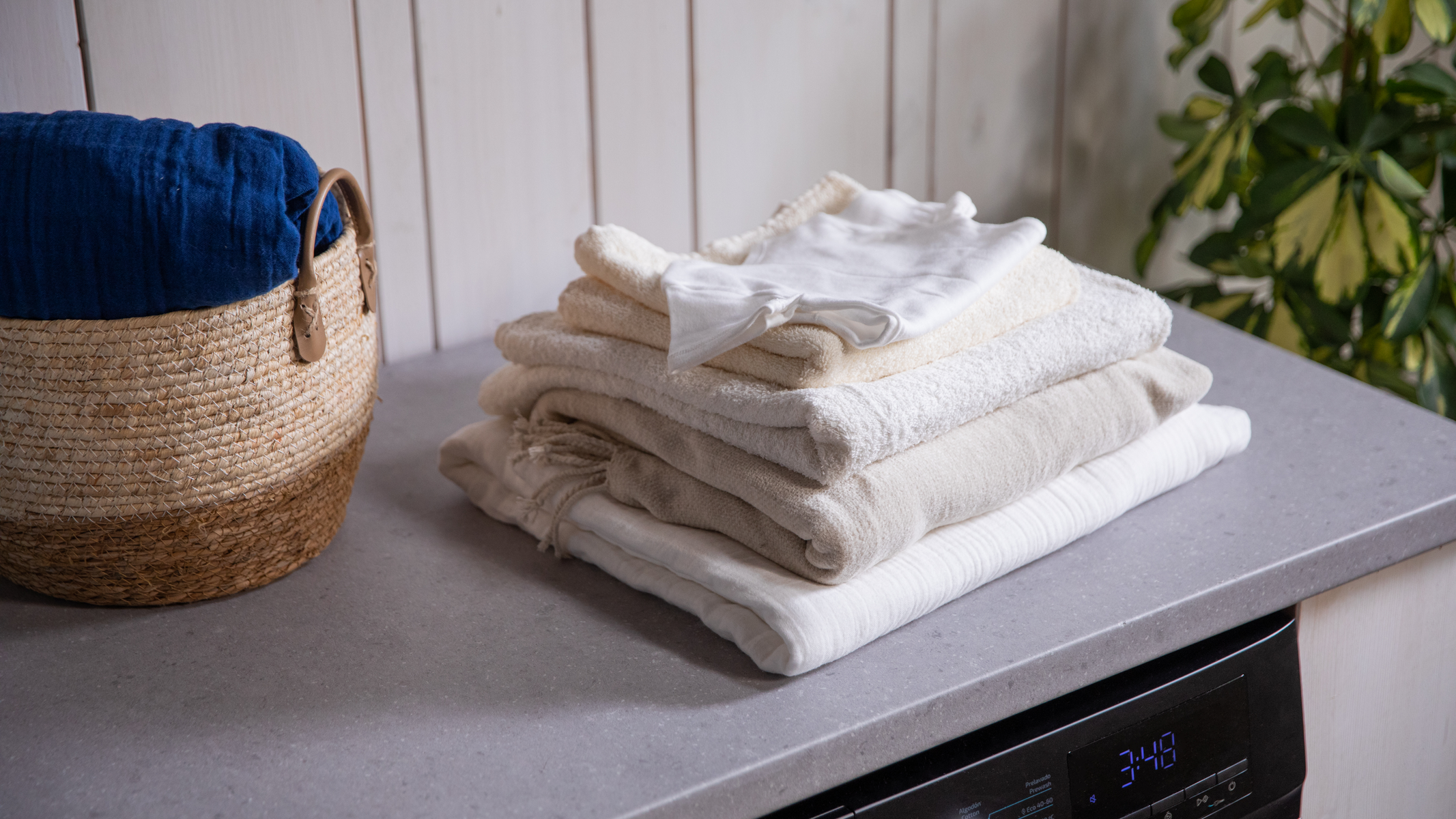 Stos złożonych ręczników i kosz na blacie. Kontekst prania.
