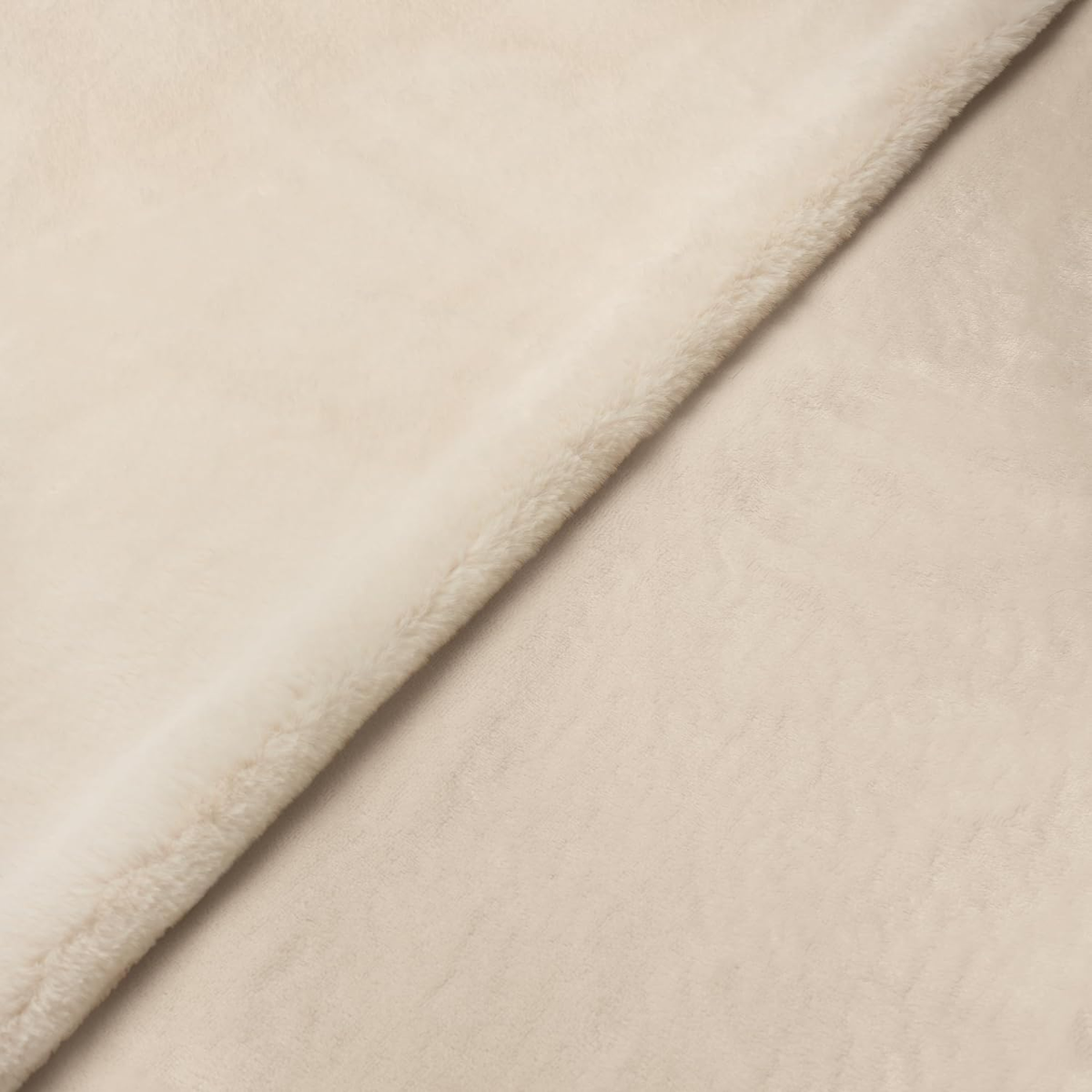 Una coperta di peluche color crema piegata.