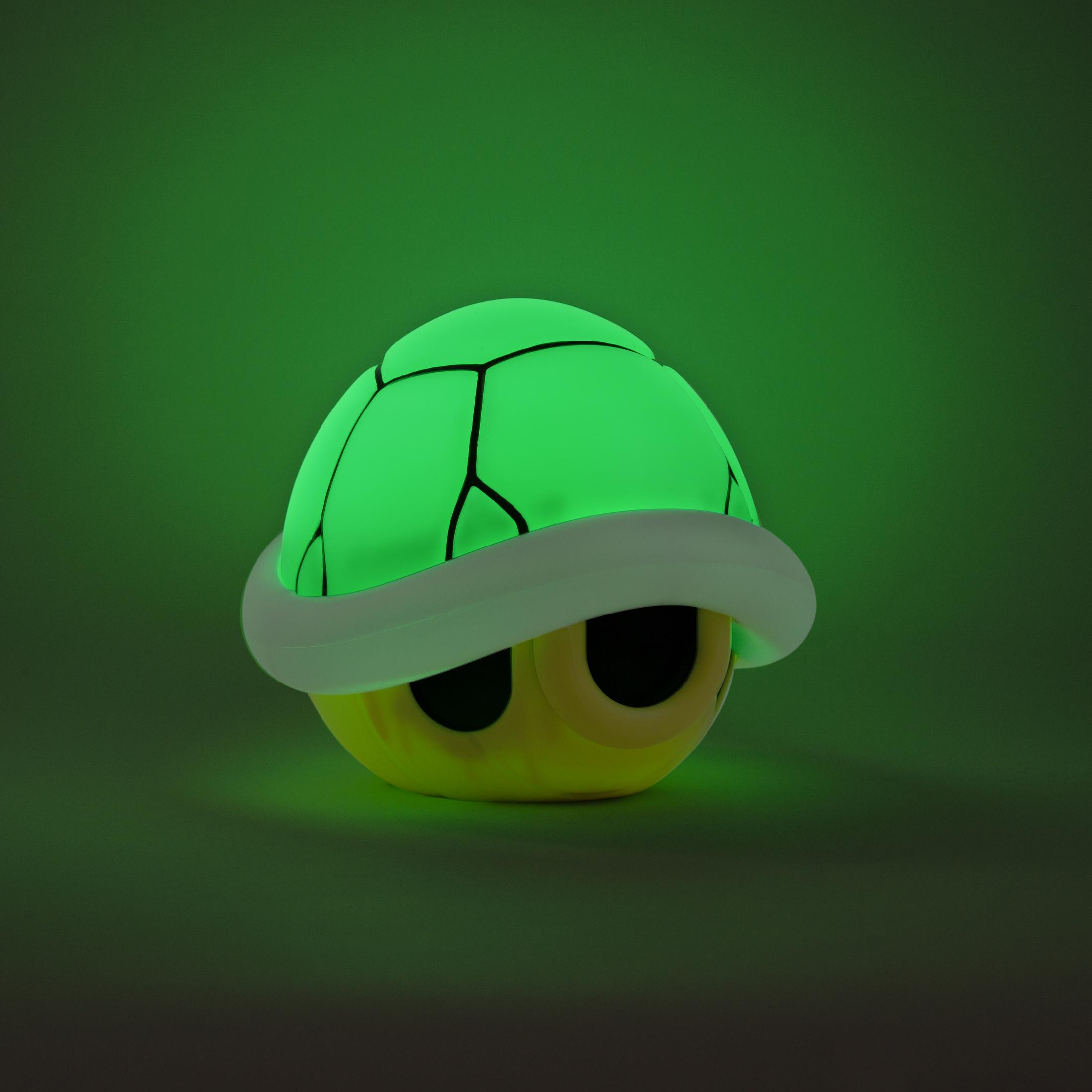 Leuchtende grüne schildkrötenförmige Lampe, gelbes Gesicht, grüner Hintergrund.